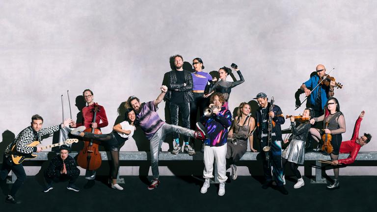 "ZDF Magazin Royale": Die Mitglieder des "Rundfunk-Tanzorchesters Ehrenfeld" stehen vor einer weißen Wand und halten ihre Instrumente in der Hand.