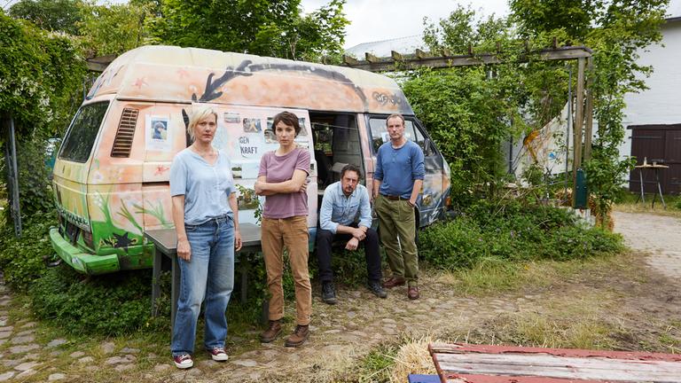 "Das verschwundene Kind": Inga Volkmann (Anna Schudt), Sophie Buchholz (Julia Koschitz), Bodo Herzog (Hans Löw) und Thies Buchholz (Mark Waschke) stehen im Hof vor einem selbst angemalten Bulli und schauen nach vorne.