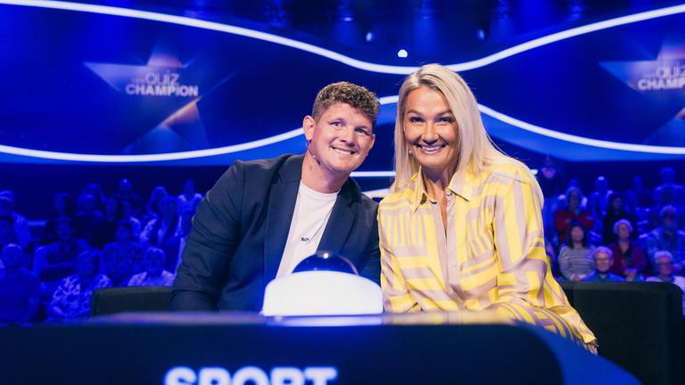 "Der Quiz-Champion - Das Österreich-Deutschland-Special": Thomas Morgenstern und Franziska van Almsick sitzen am Ratepult und lächeln in die Kamera. Im Hintergrund sitzt das Publikum.