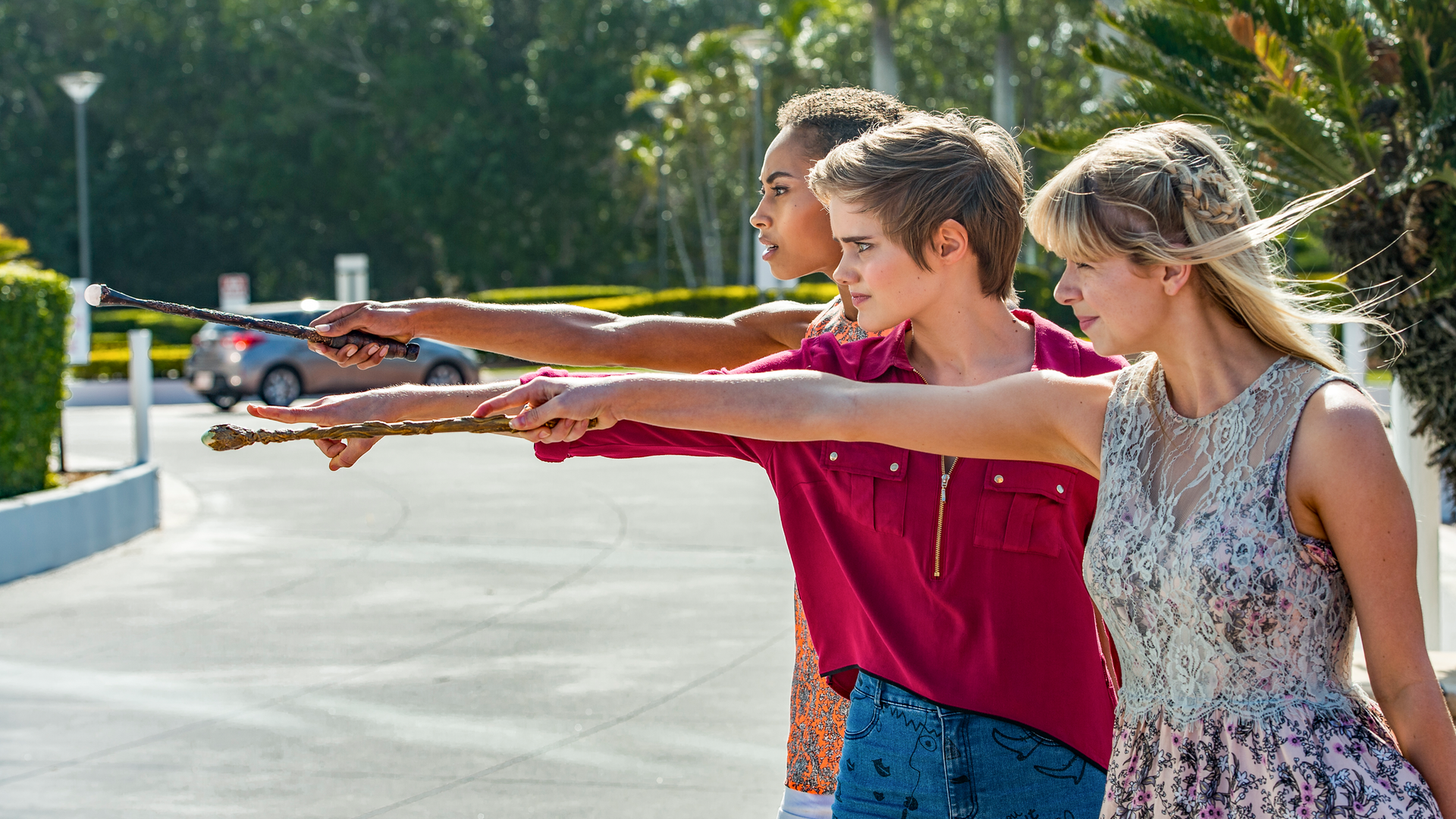 Ruksy, Lily und Imogen stehen mit ausgetreckten Armen zaubernd auf einer Straße.
