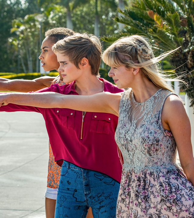 Ruksy, Lily und Imogen stehen mit ausgetreckten Armen zaubernd auf einer Straße.