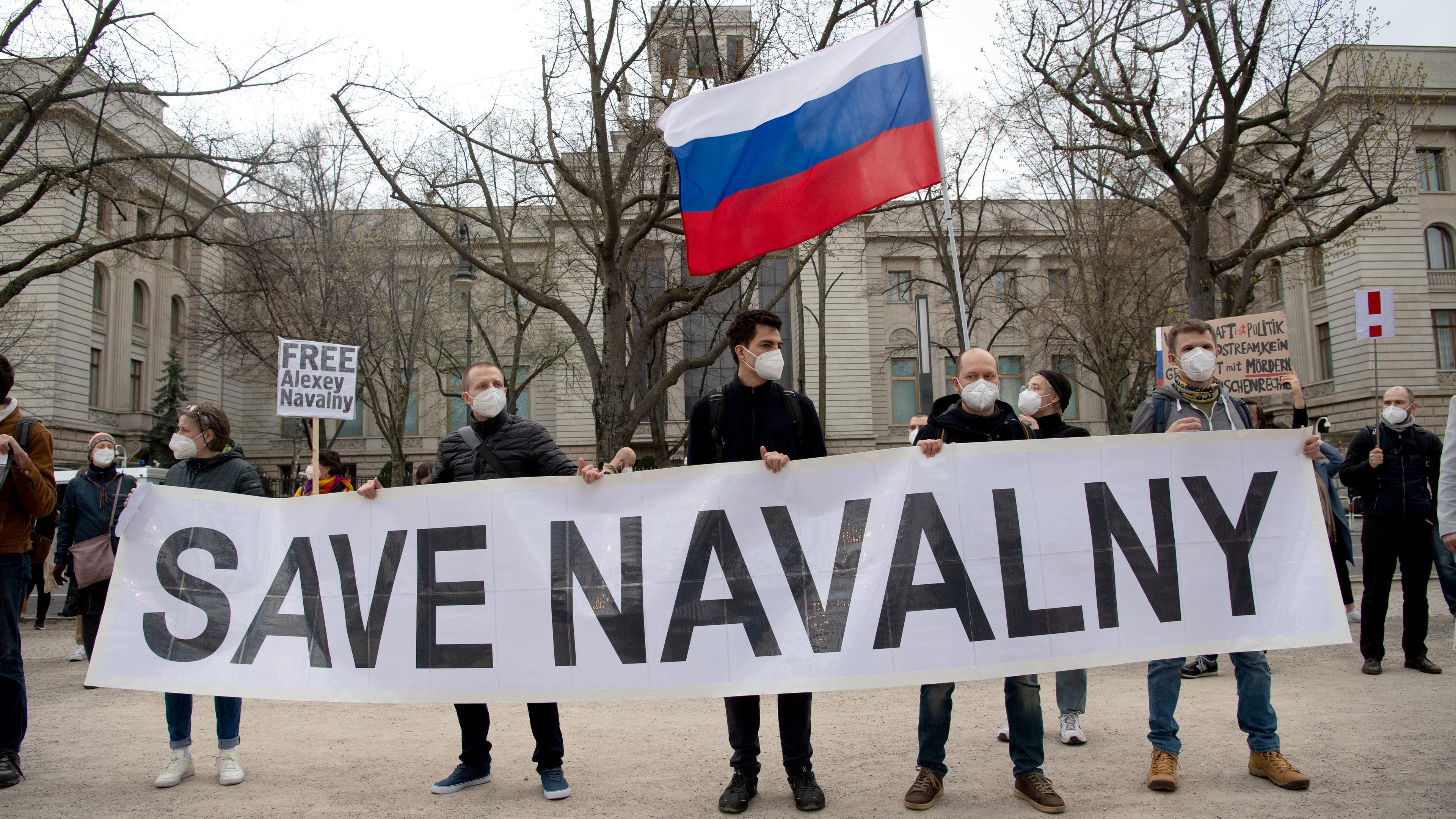 Demonstranten halten schild hoch. Auf dem steht "SAVE NAVALNY"