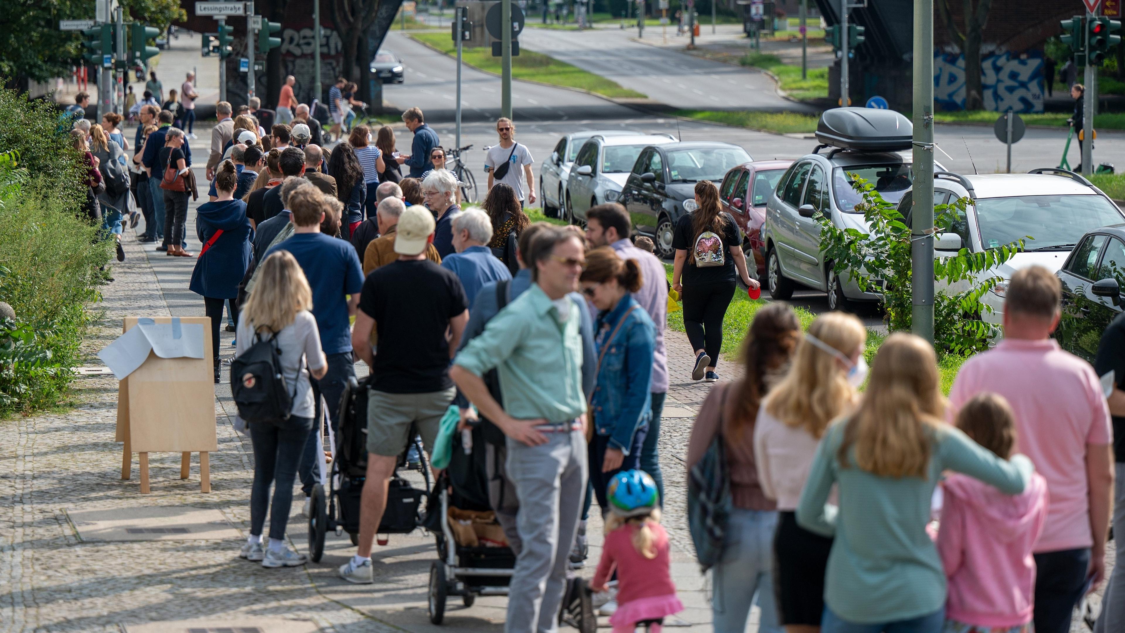 26.09.2021, Berlin: Dutzende Menschen stehen hintereinander in einer Schlange.