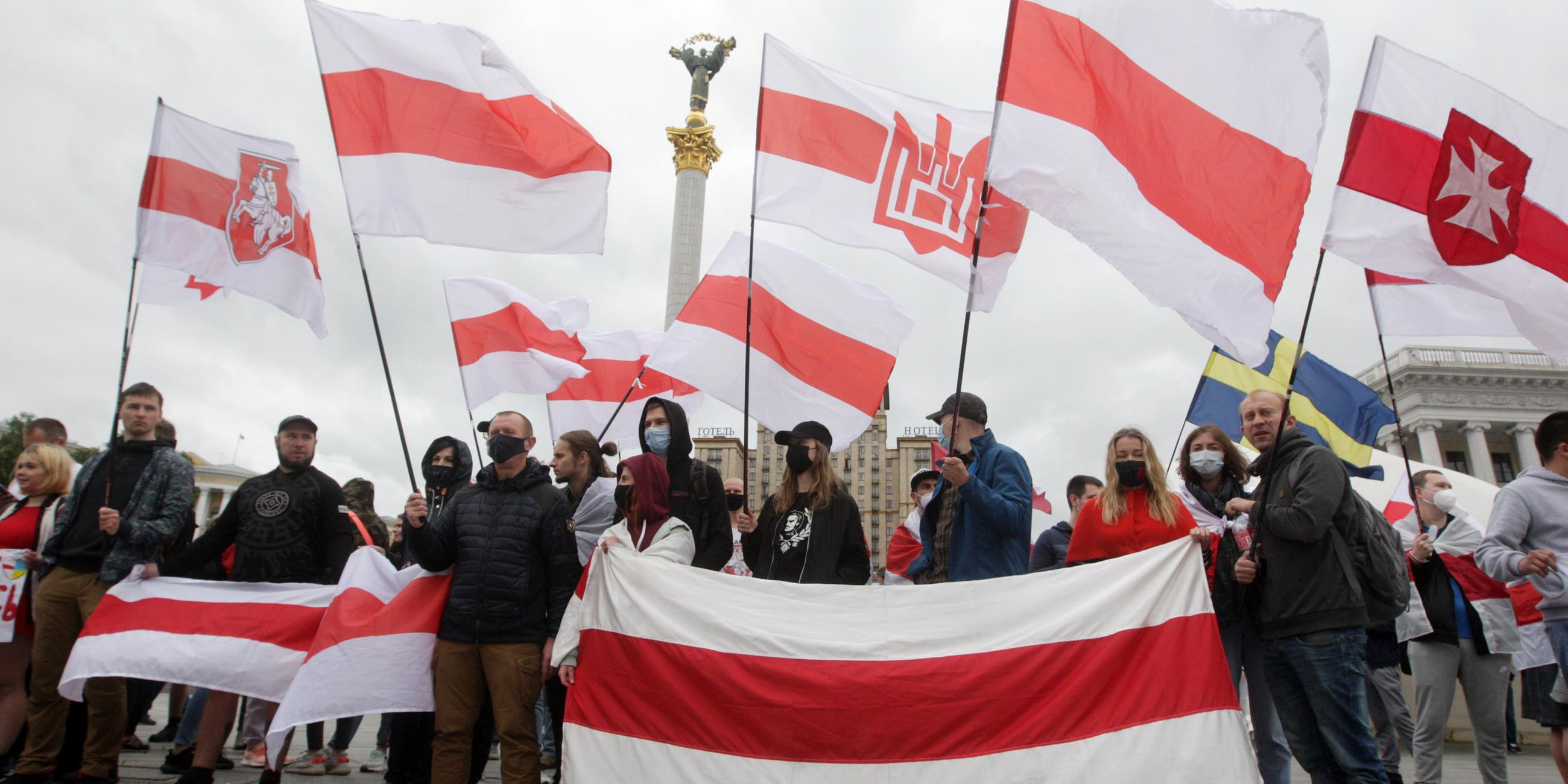 Demonstranten halten historische belarussische Fahnen in die Höhe