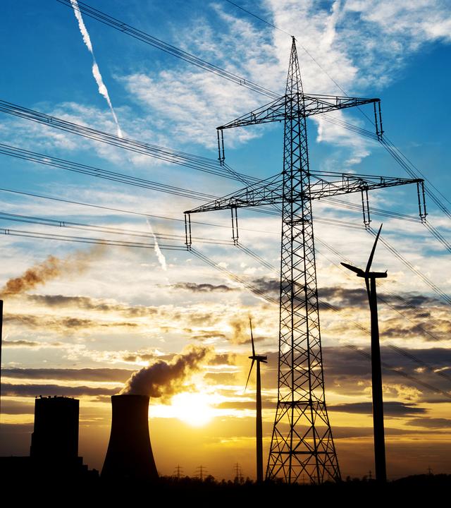 Fossiles Kraftwerk und Windkraftanlage im Sonnenuntergang