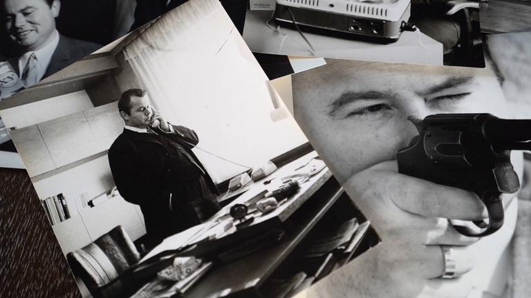 Auf einem Tisch liegen mehrere Fotos von Eduard Zimmermann. Mal telefoniert er, mal schaut er durch eine Pistole oder liest lächelnd ein Buch.