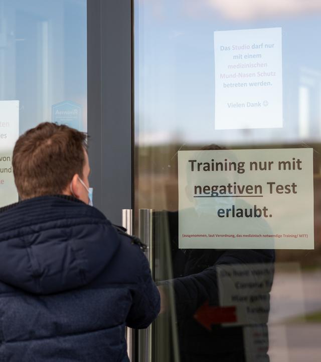 Mann stehrt vor Eingang zu Fitnessstudio