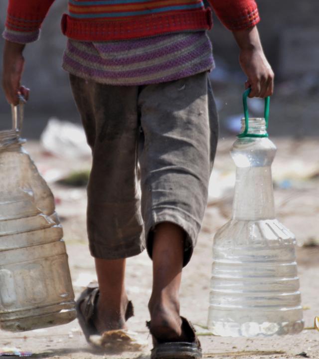 Junge schleppt Wasserkanister