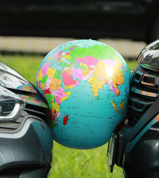 Autos zerwetschen einen Ball, der die Erde darstellt