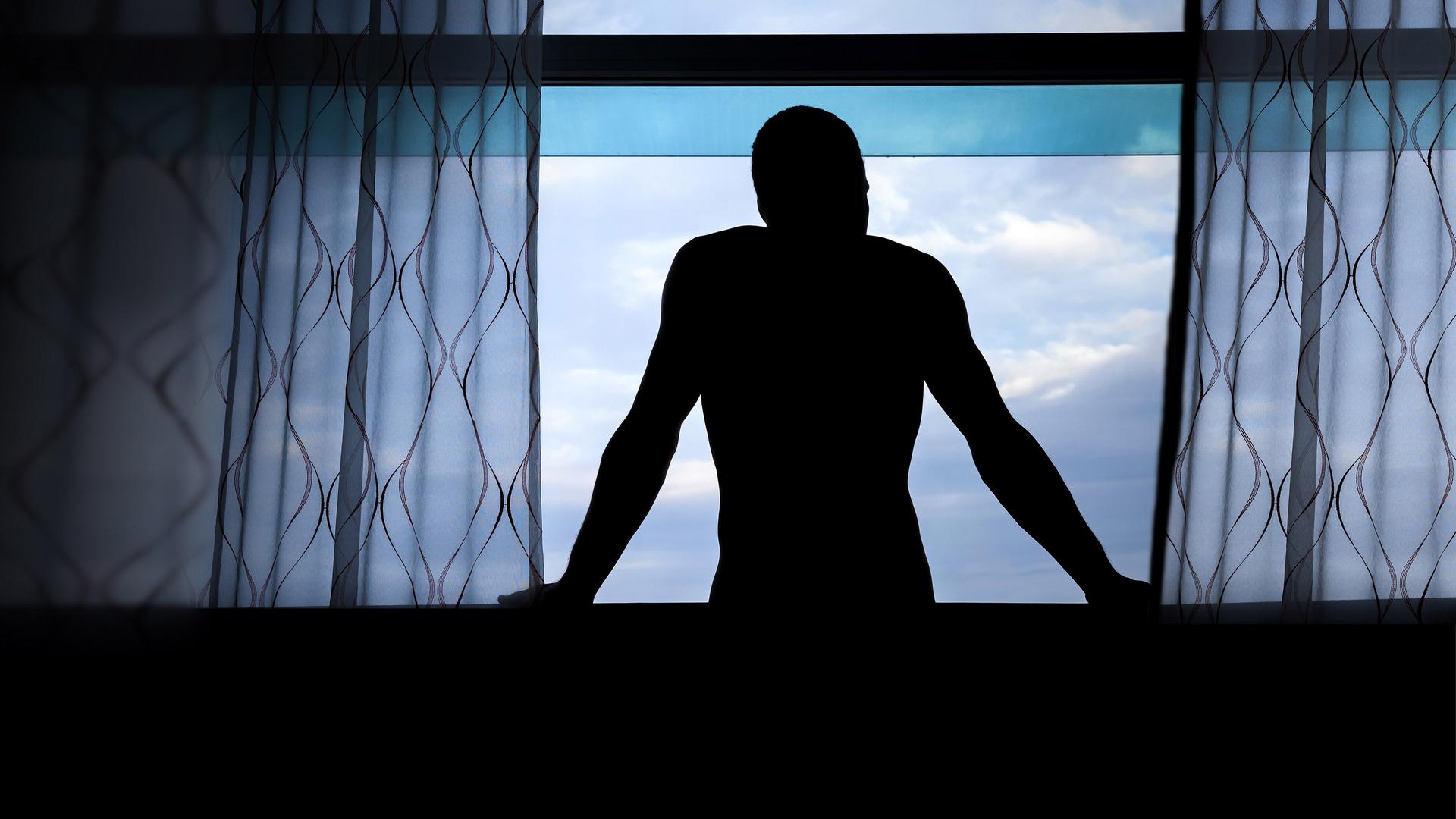 Dunkle Männersilhoulette an einem Fenster 