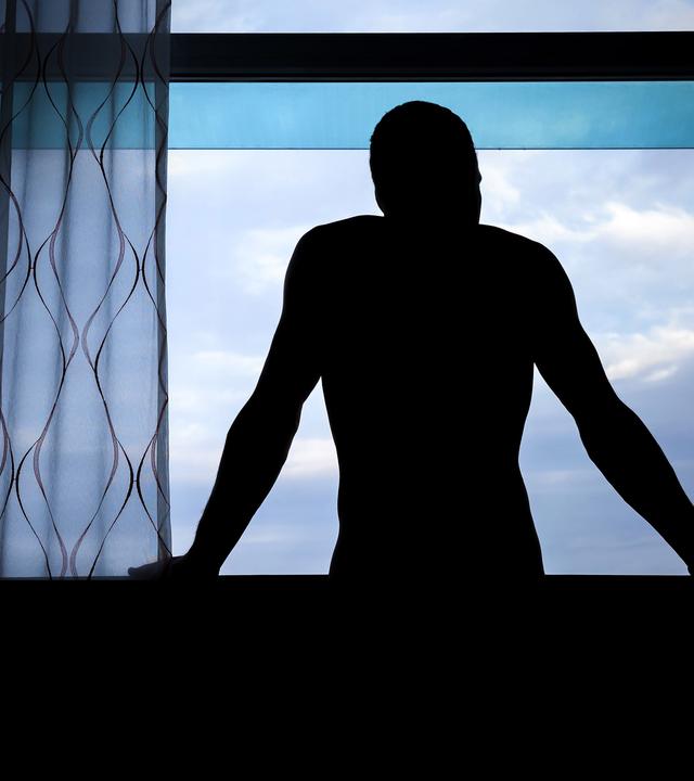 Dunkle Männersilhoulette an einem Fenster 