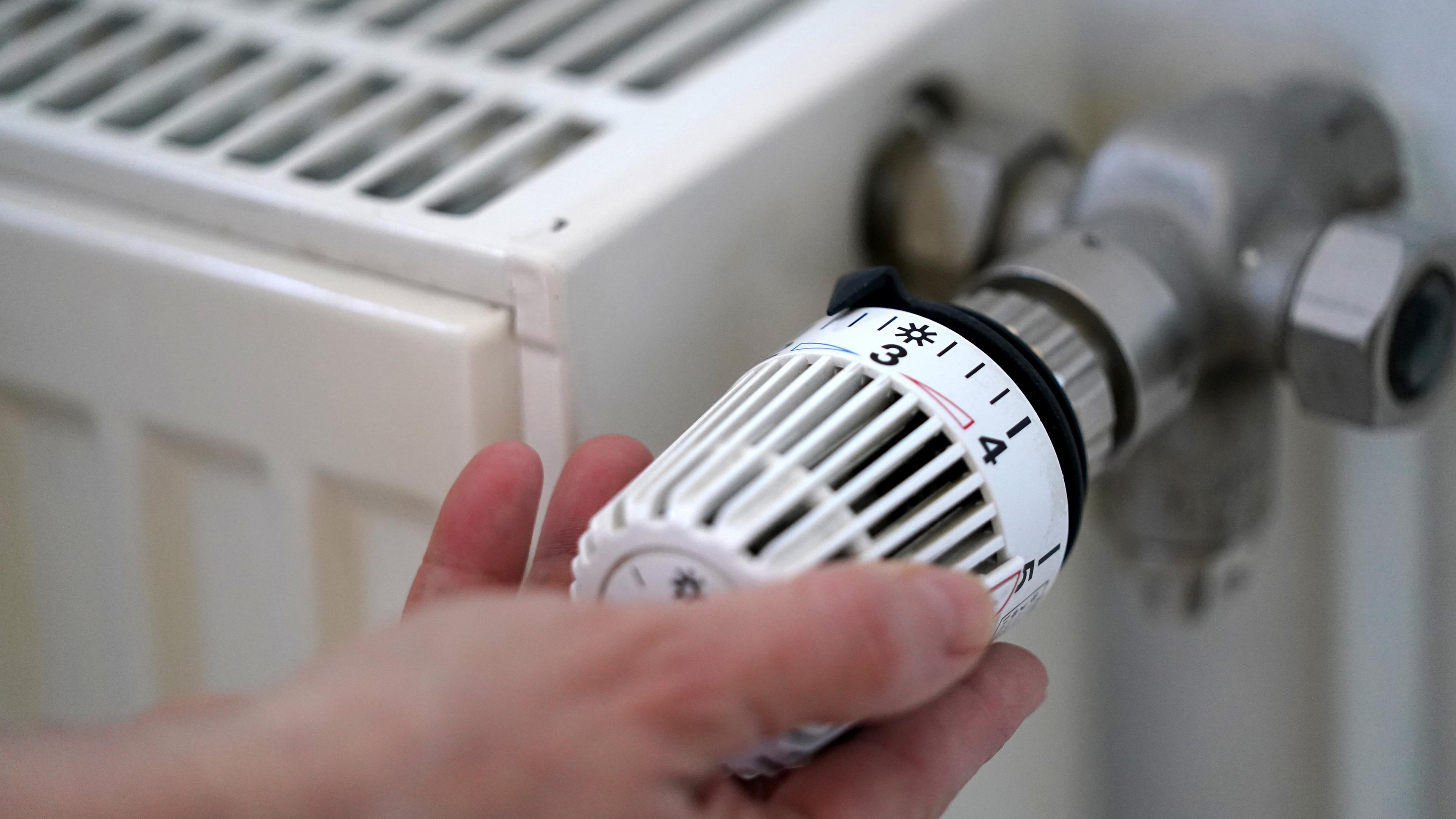 Eine Frau dreht an der Heizung in ihrer Wohnung. Für Verbraucher*innen ist noch nicht klar, wie hoch die Heizkosten diesen Winter tatsächlich sein werden, Symbolbild, 09.03.2022, Hamburg.