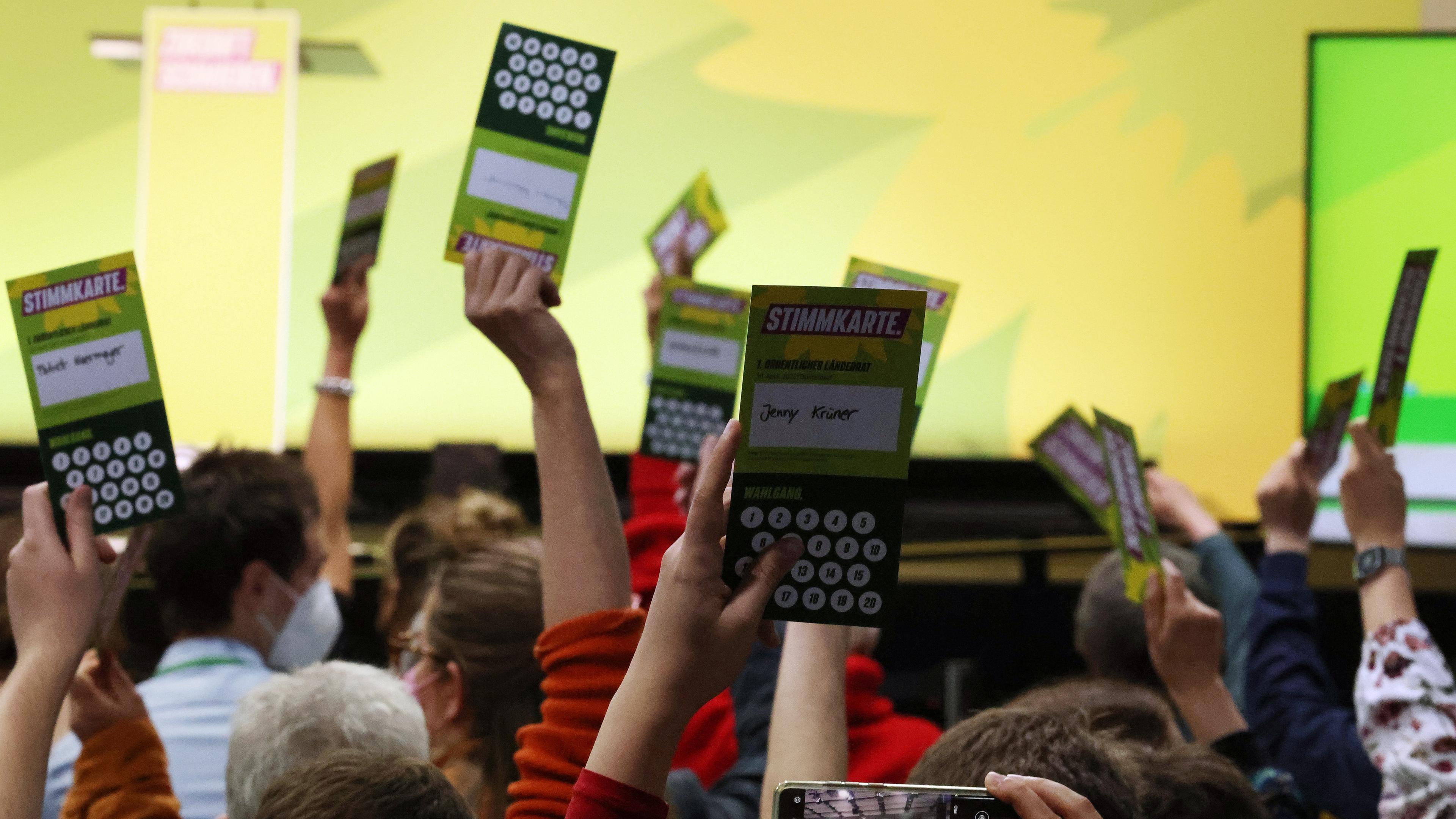 Düsseldorf, 30.04.2022: Hände die grüne Stimmkarten in die Luft halten