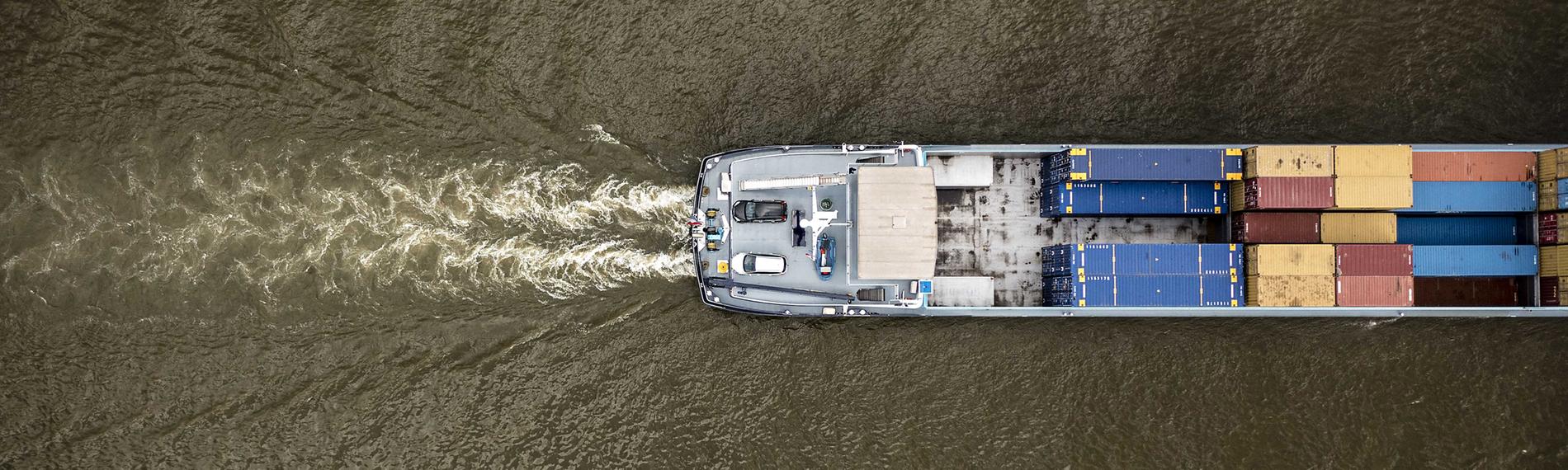 18.08.2022, Rhein bei Lobith, Niederlande: Ein Binnenschiff fährt durch den Rhein (aufgenommen aus der Vogelperspektive)