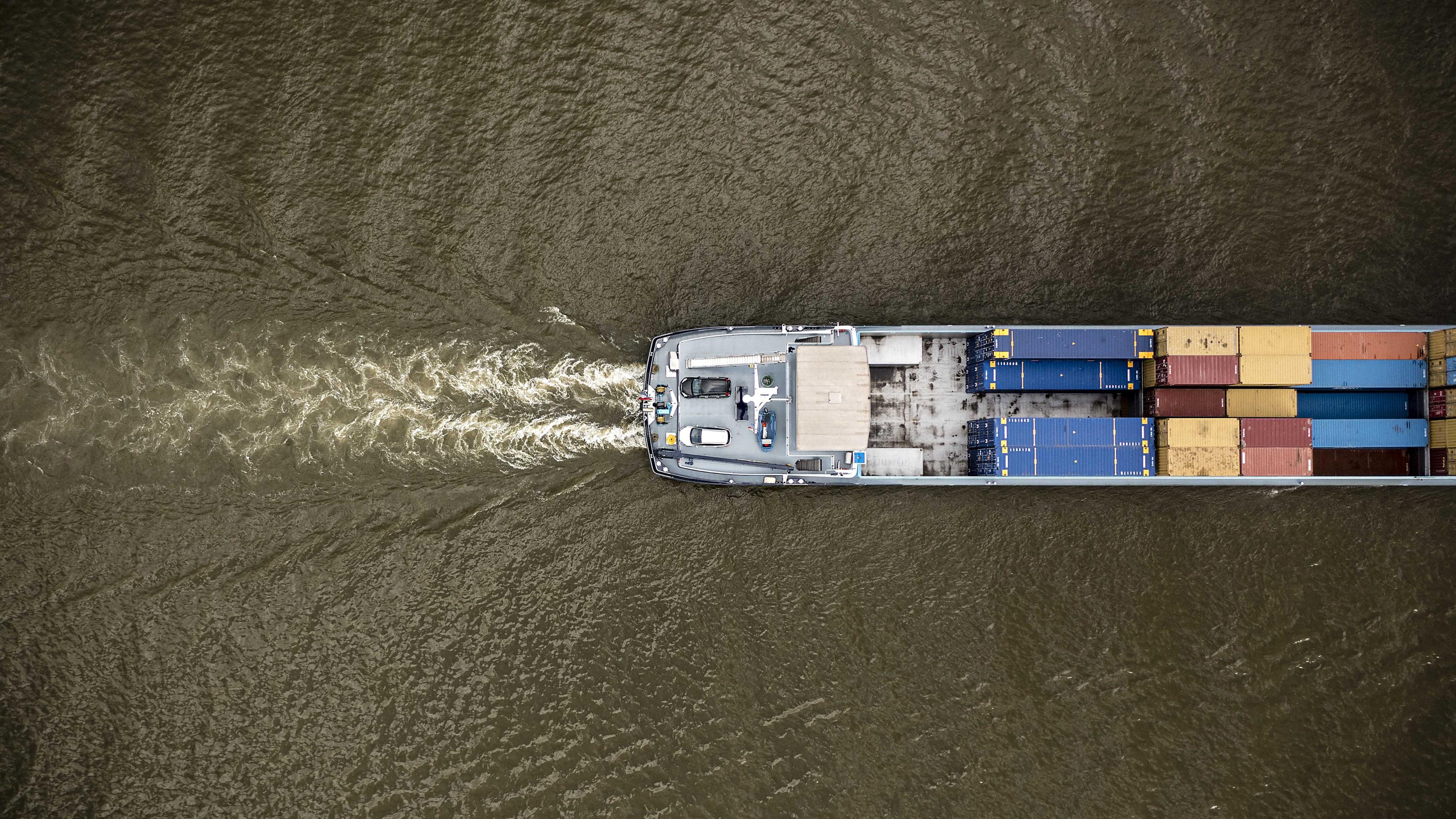 18.08.2022, Rhein bei Lobith, Niederlande: Ein Binnenschiff fährt durch den Rhein (aufgenommen aus der Vogelperspektive)