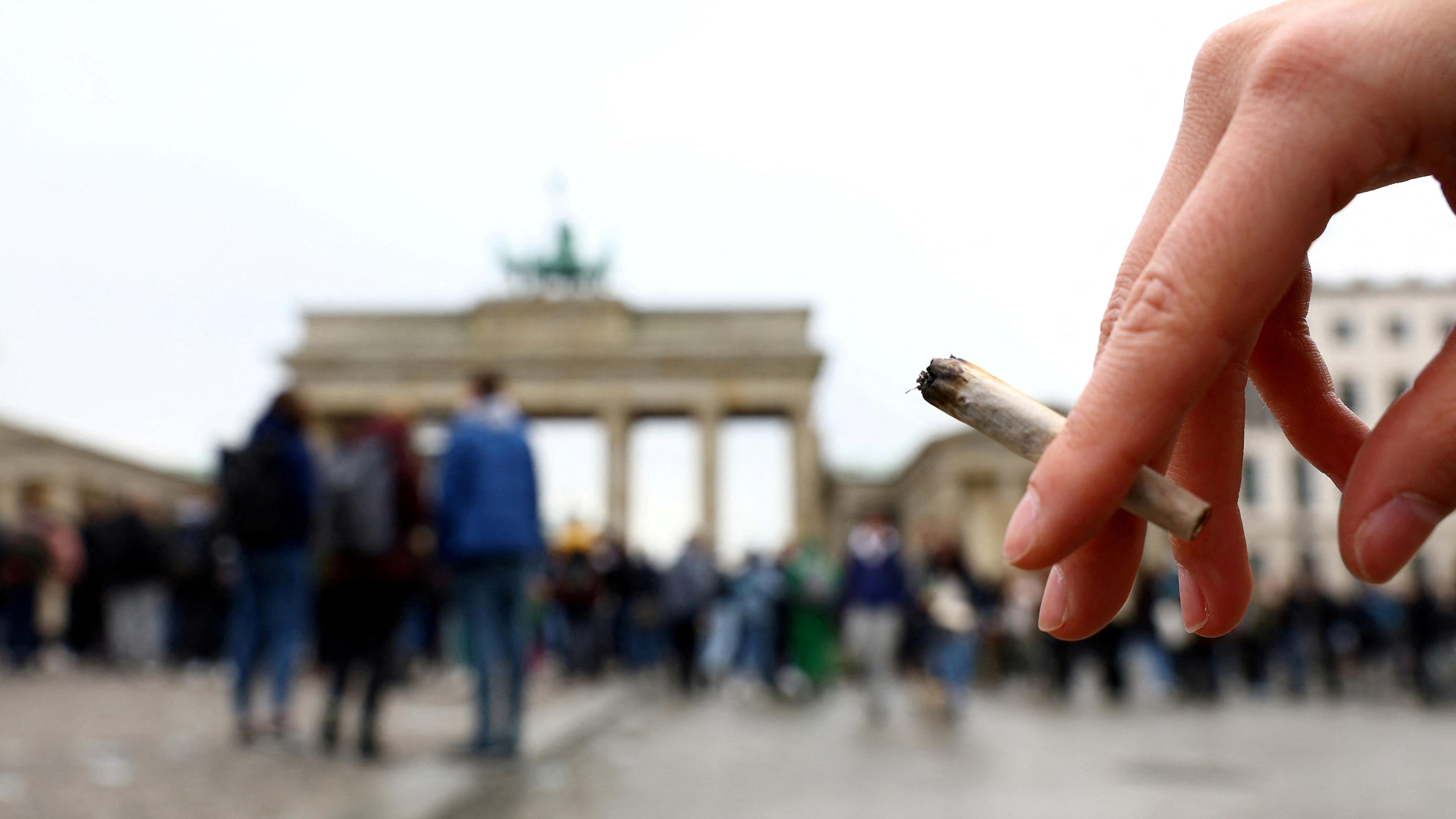 Eine Person steht am Brandenburger Tor in Berlin und hält einen Joint in der Hand. Berlin, 26.10.2022.