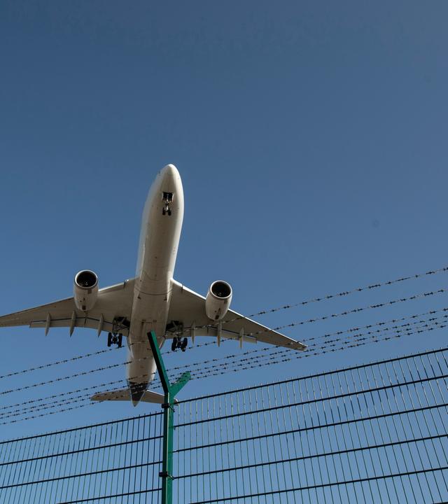 Flugzeug fliegt über einen Zaun