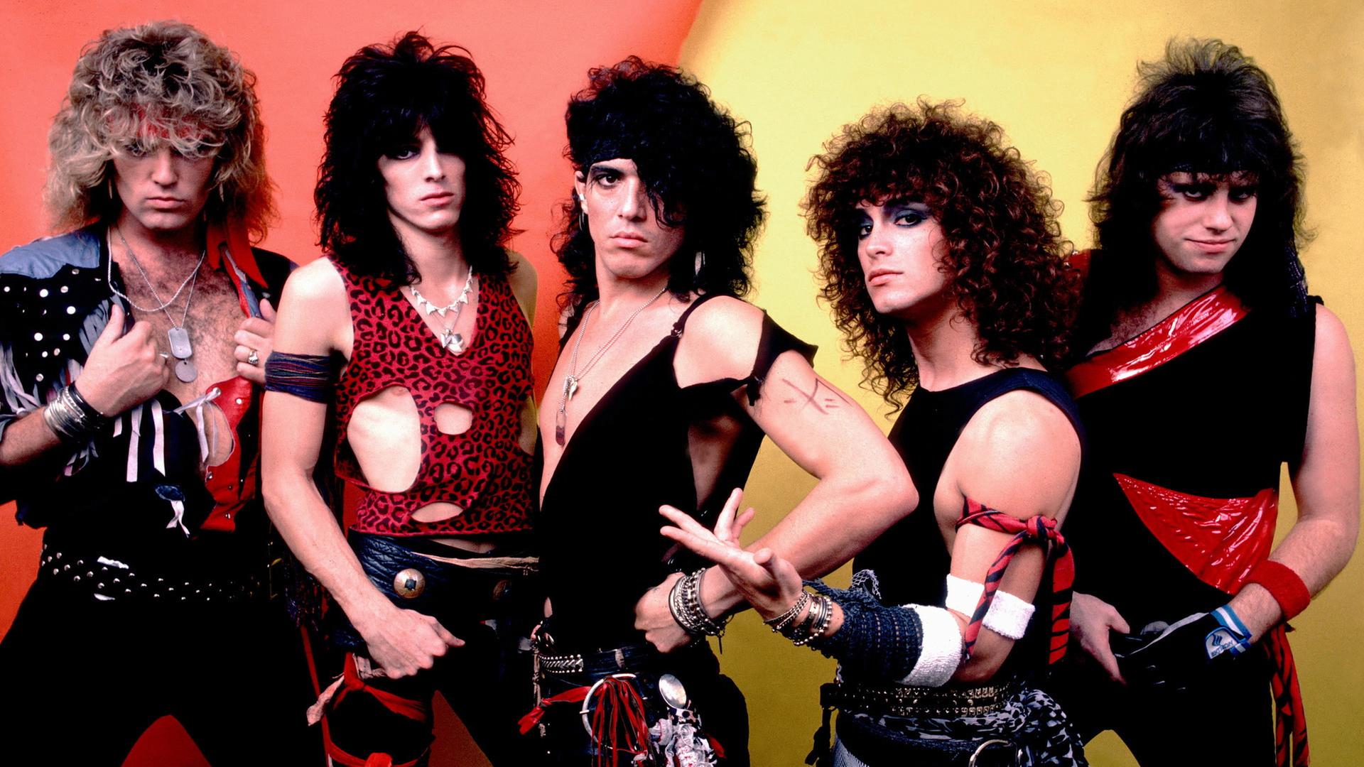 "The Story of Hair Metal (3/3)": Fünf Männer mit toupierten Haaren und bunter Kleidung posen vor der Kamera.