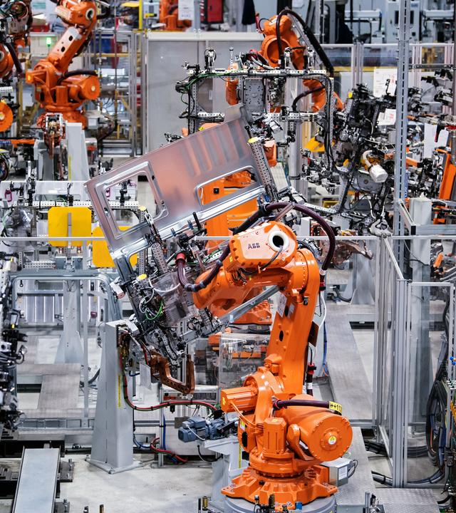 Orange lackierte Roboter arbeiten bei MAN an Fertigung von LKW