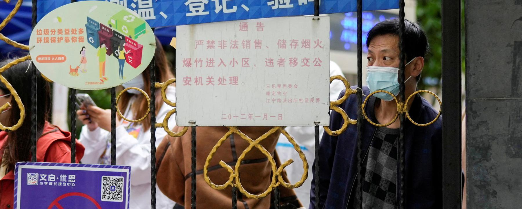 Chinesen vor einer Absperrung zu einem Wohngebiet