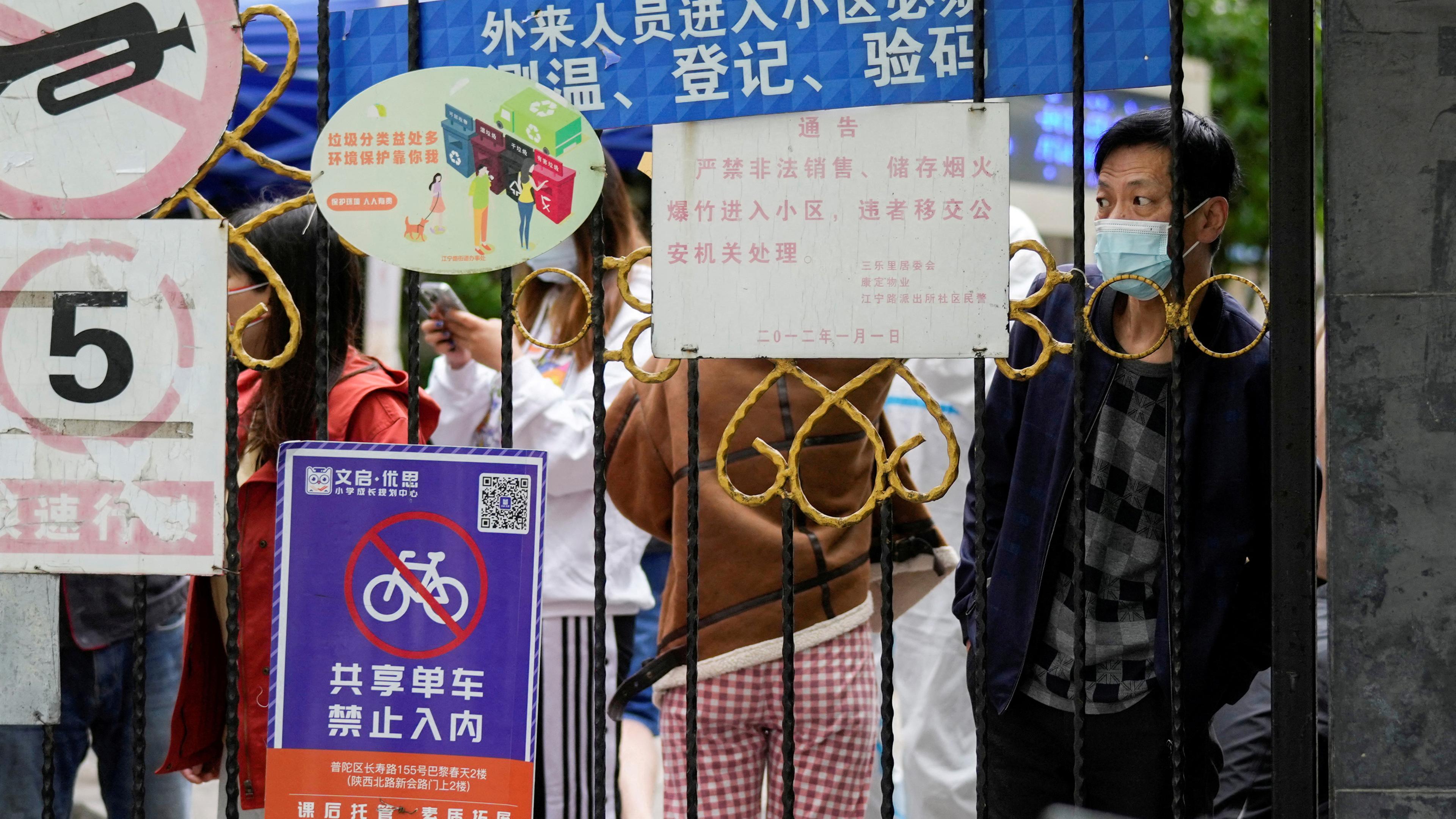 Chinesen vor einer Absperrung zu einem Wohngebiet