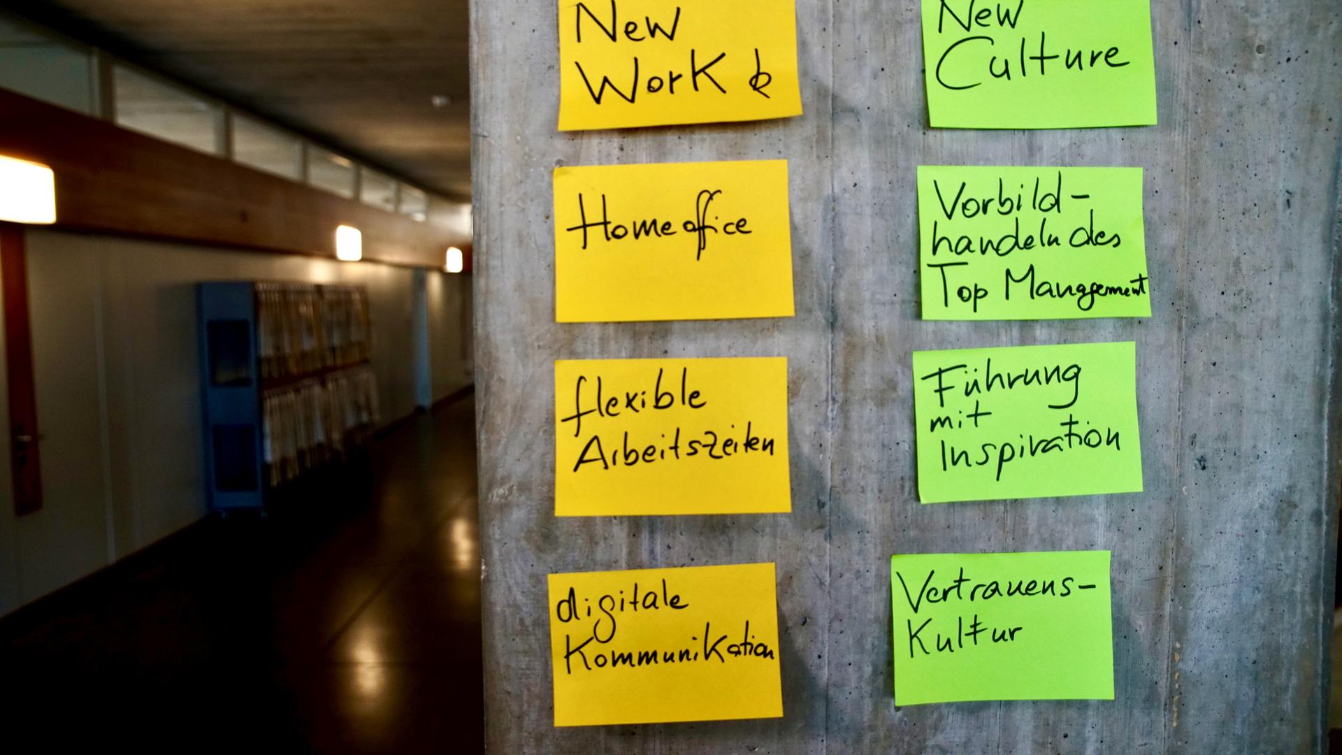  An einer Betonwand kleben Post-Its mit Stichwörtern in verschiedenen Farben.