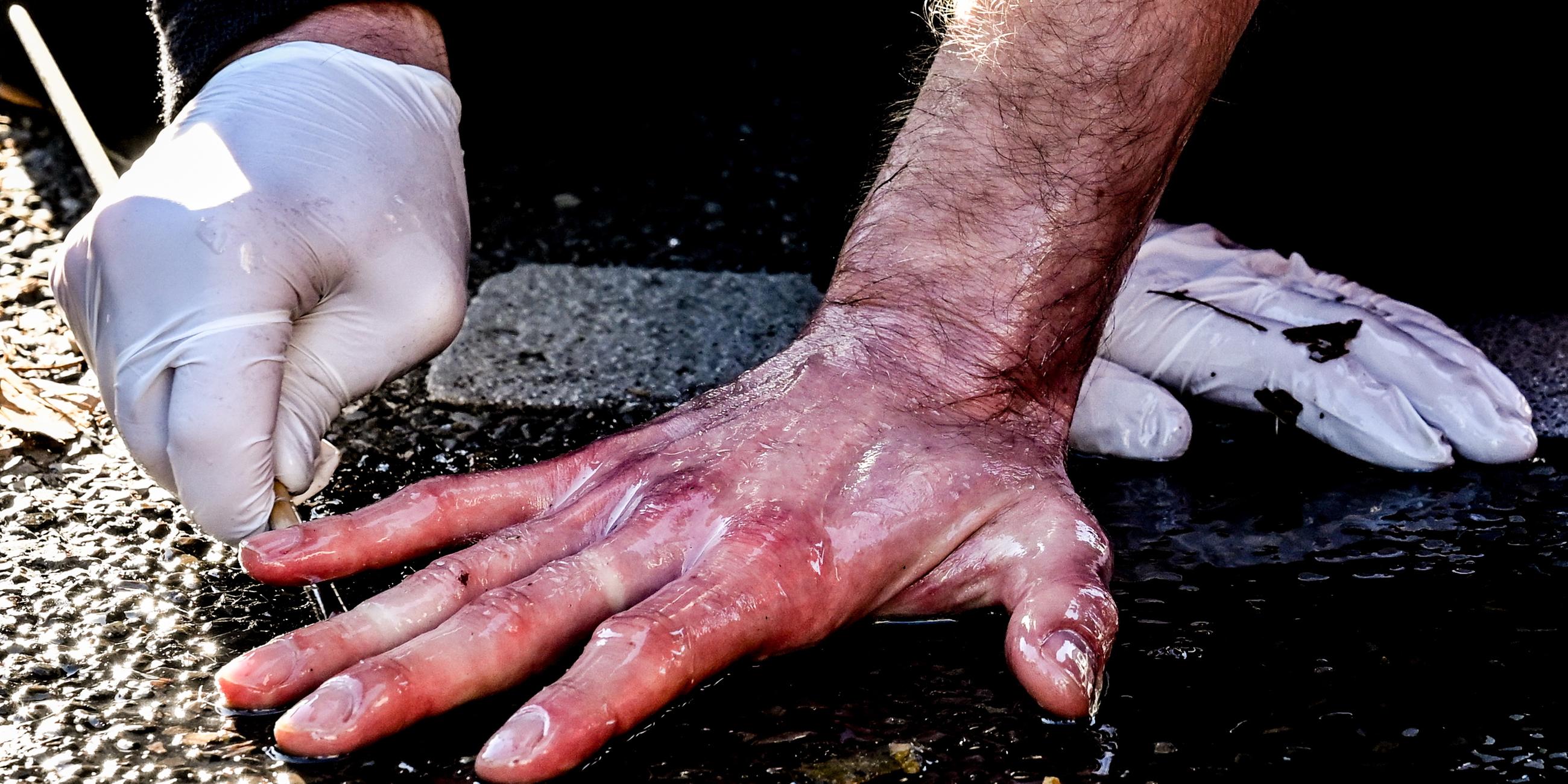 Hand eines Klimaaktivisten festgeklebt auf einer Straße