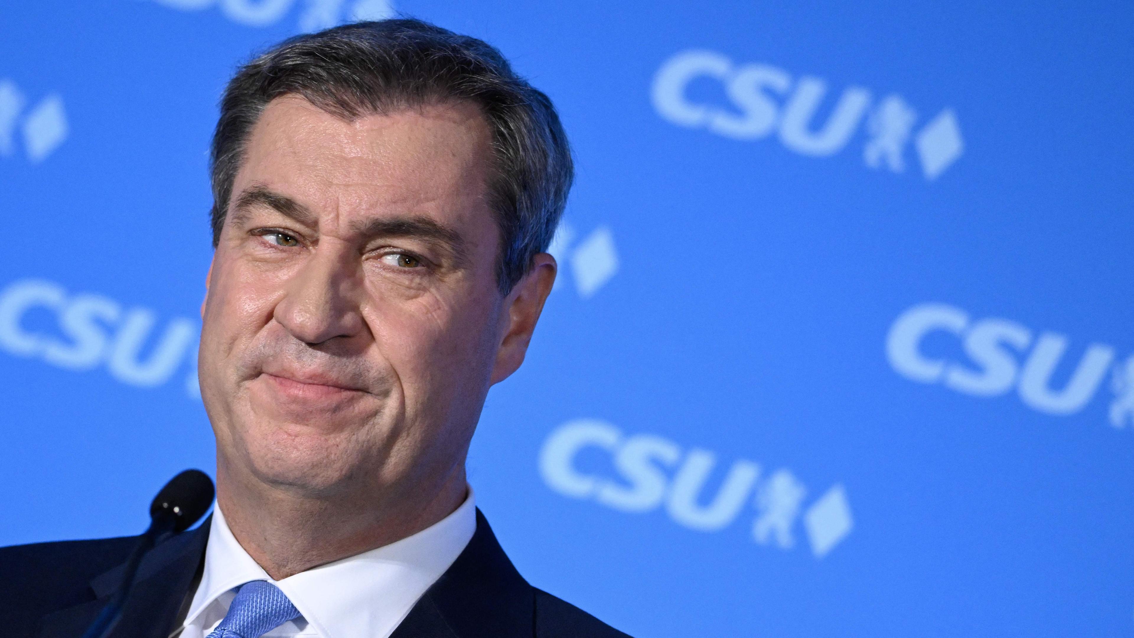 08.10.23, München: Bayerns Ministerpräsident Söder steht vor einem blauen Hintergrund, auf dem in weißer Schrift CSU steht.