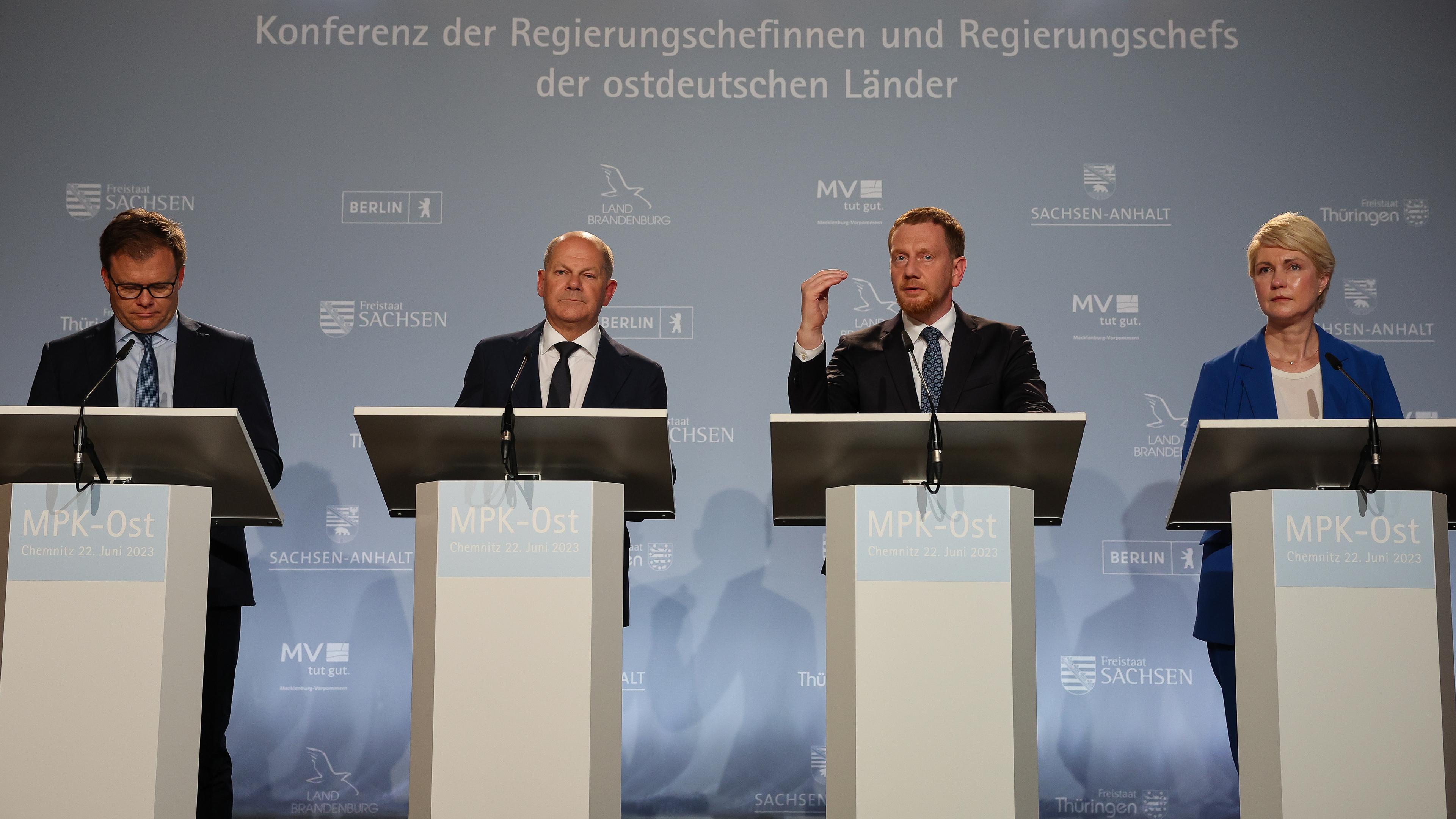 22.06.23, Chemnitz: Bundeskanzler Olaf Scholz, Michael Kretschmer und Manuela Schwesig stehen vor Rednerpulten auf einer Pressenkonferenz.