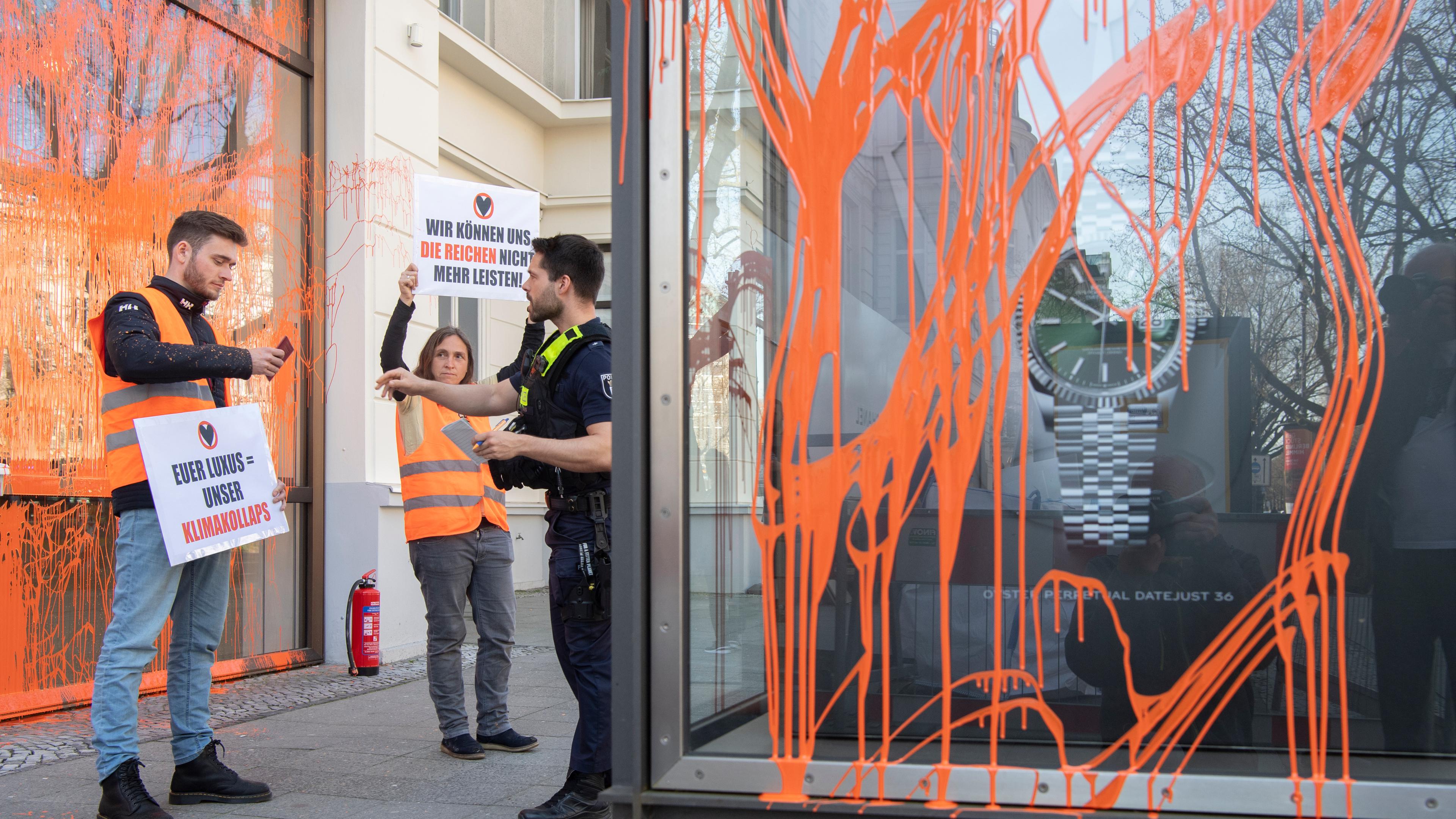 Aktivisten der Umweltschutzgruppe Letzte Generation halten vor einem Geschäft Plakate. Berlin, 22.04.2023