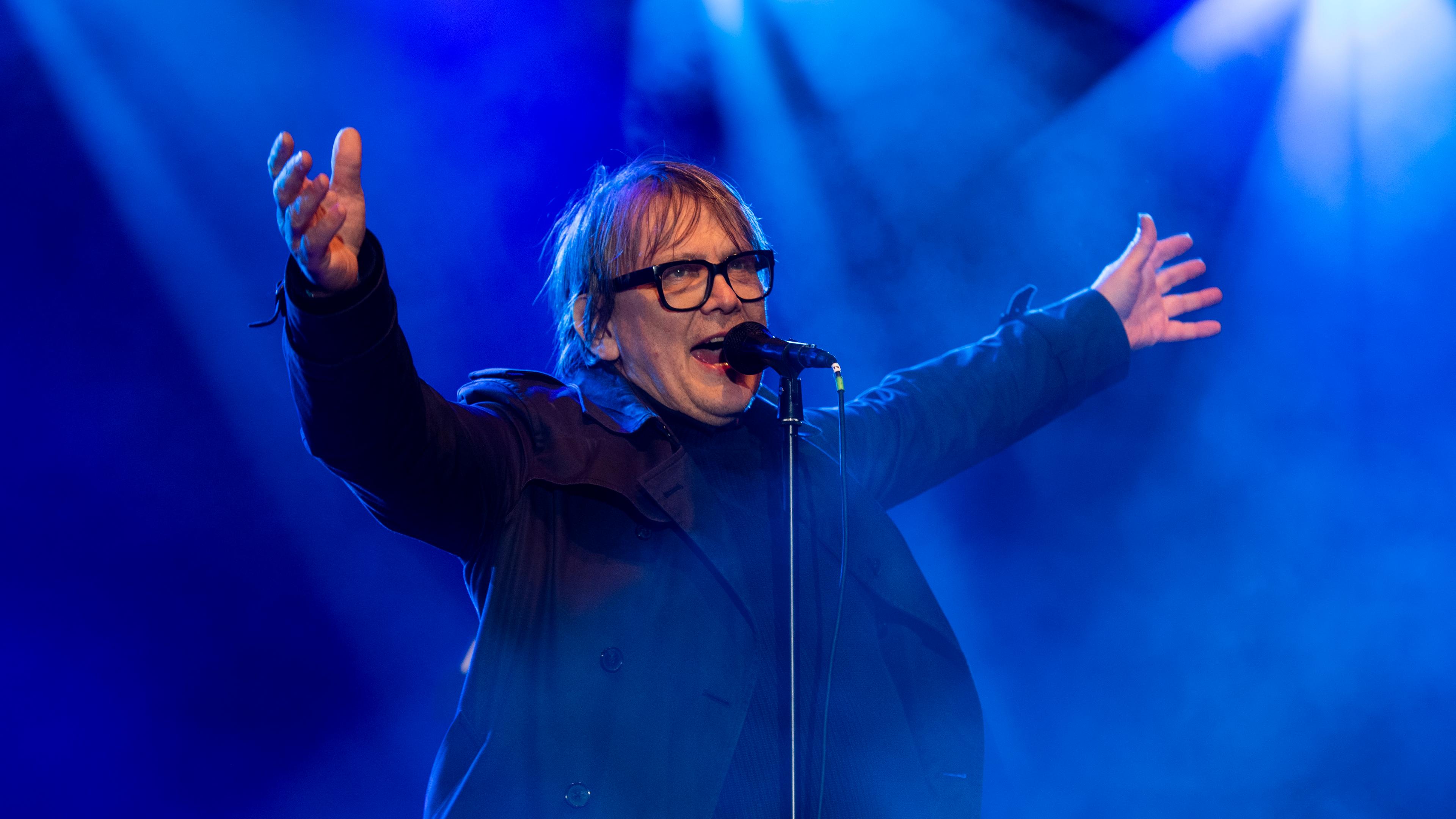 ARCHIV, 25.03.23, Berlin: Der Frontmann der Band Element of Crime singt bei einem Konzert unter blauem Scheinwerferlicht in ein Mikrofon.