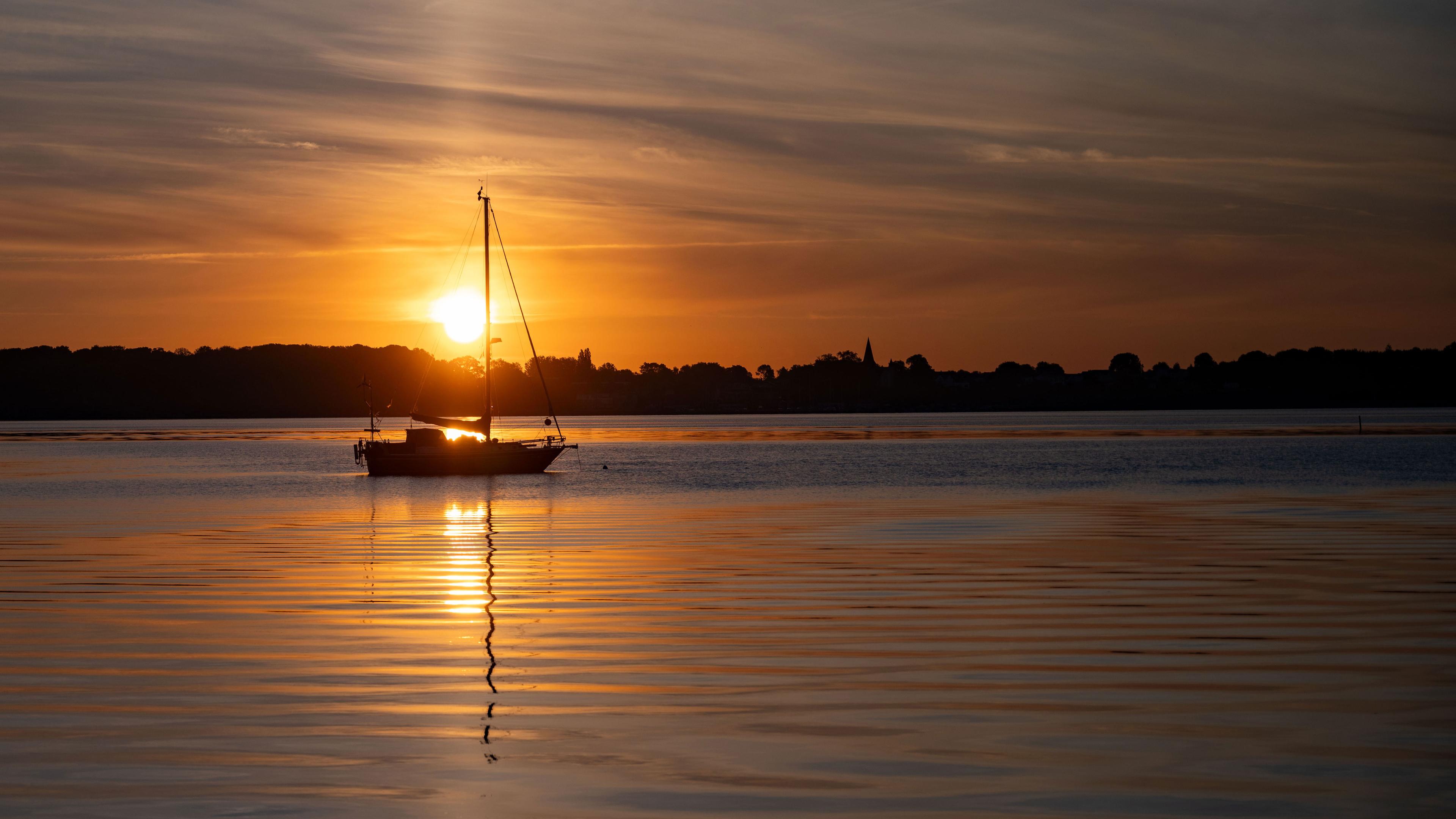 Ein kleines Segelboot auf dem Wasser bei Sonnenuntergang