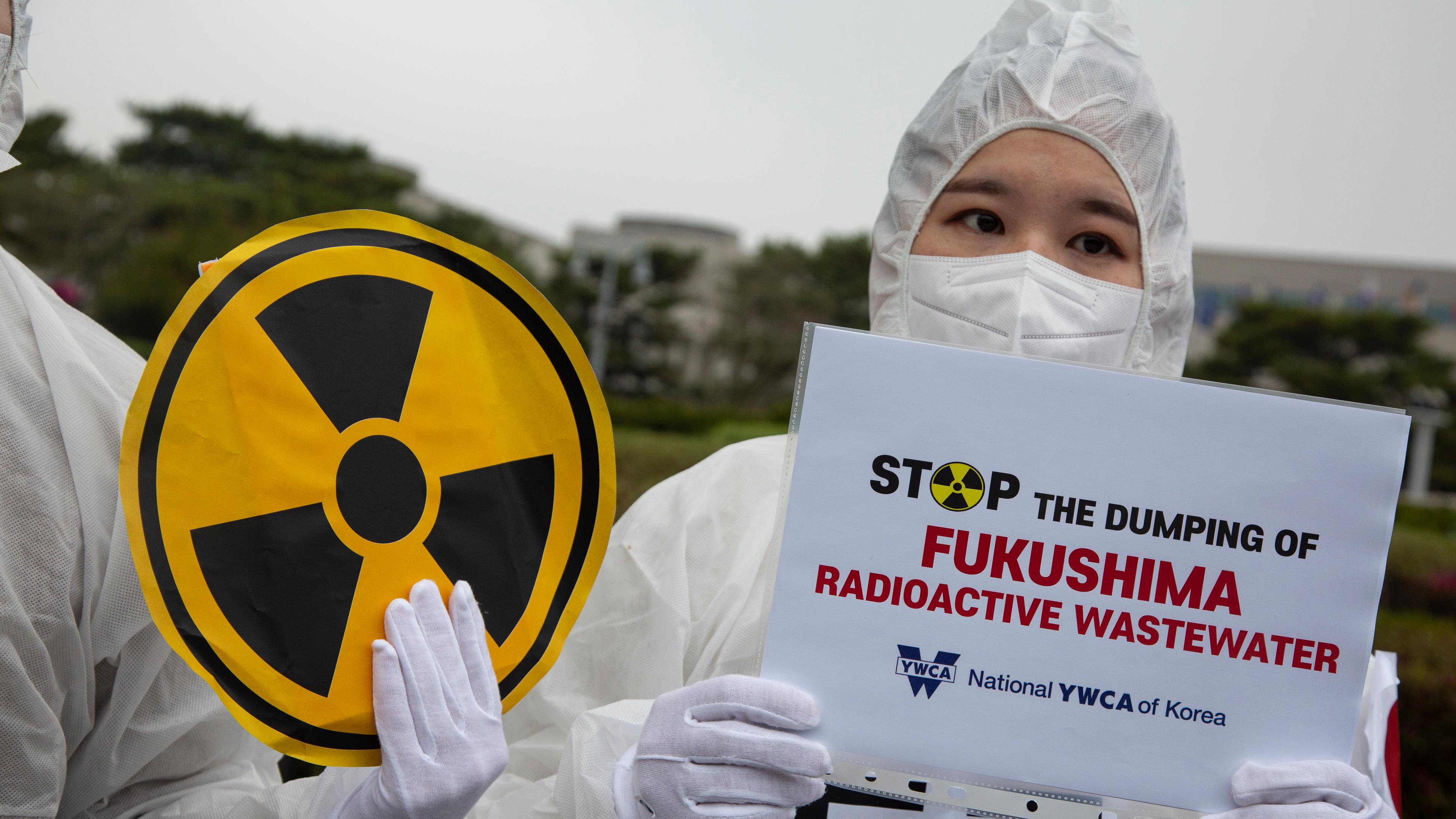 06.04.2023, Fukushima, Japan: Protestierende halten Schilder gegen die Reaktor-Kühlwasserentsorgung vor die Kamera.