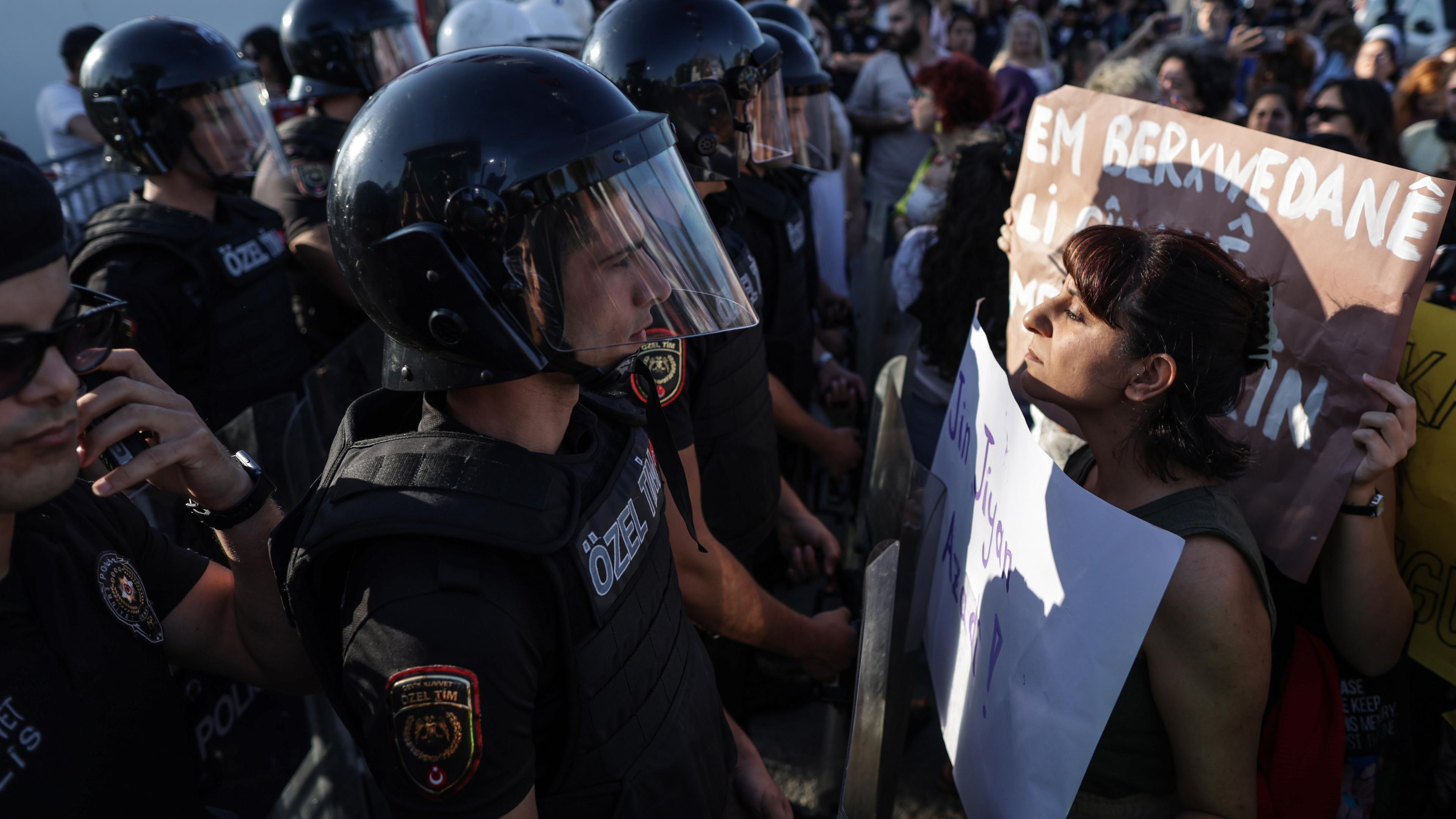 Man sieht eine Demonstrantin vor einem Polizisten.
