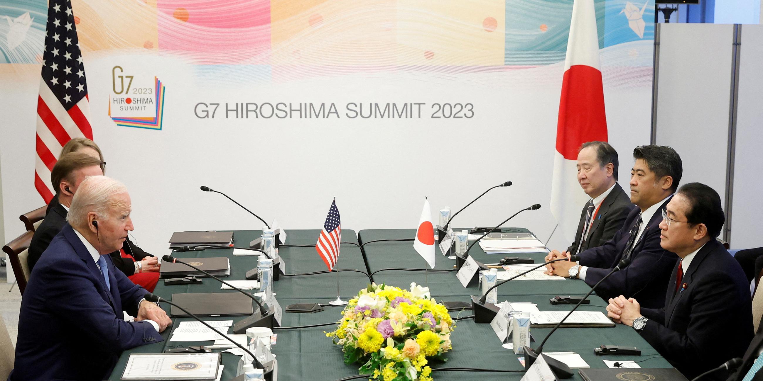An einem Tisch sitzt Joe Biden mit Japans Prime Minister Fumio Kishida