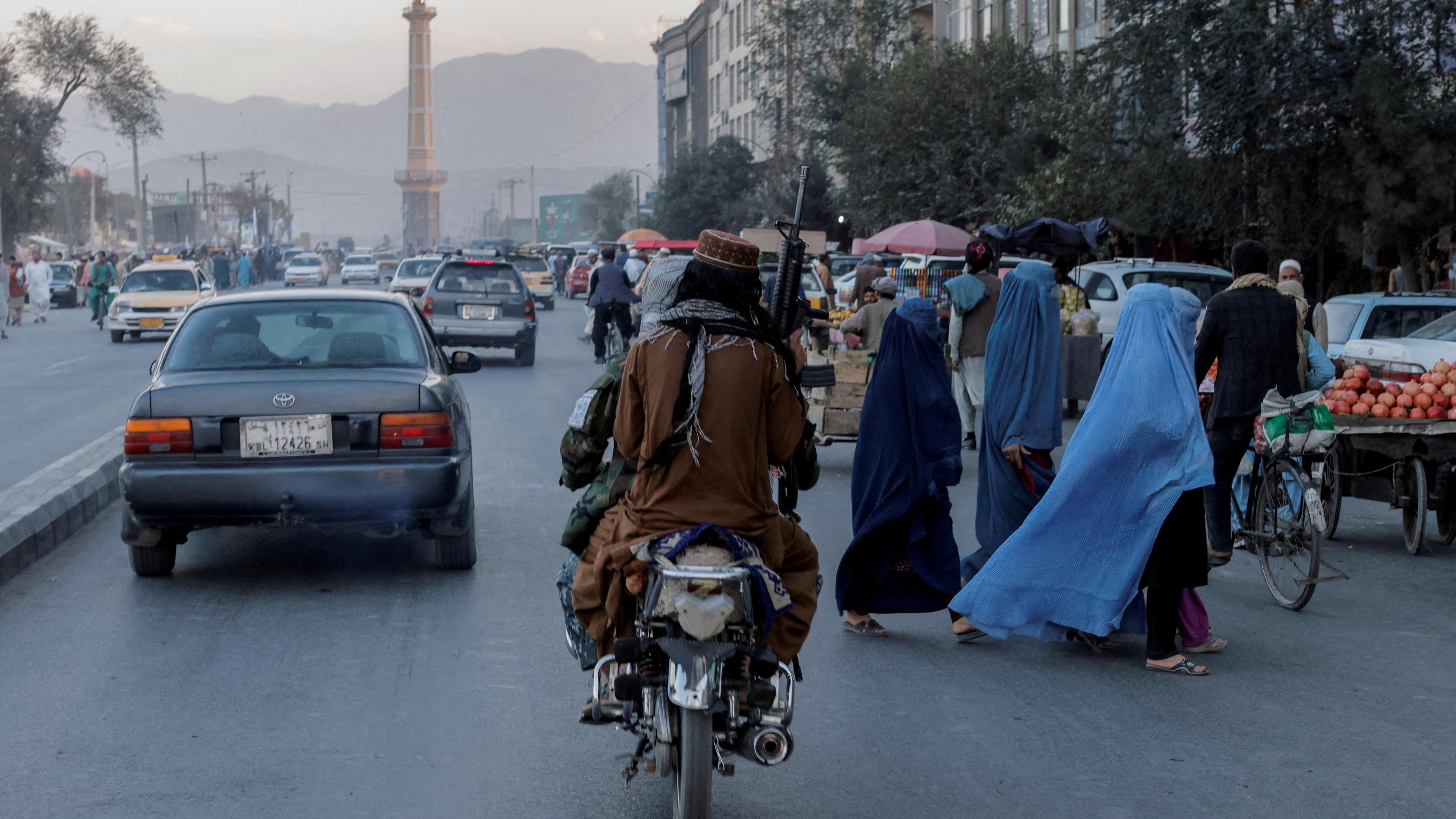 Frauen überqueren die Straße während die Taliban vorbeifahren. Kabul, 28.04.2023