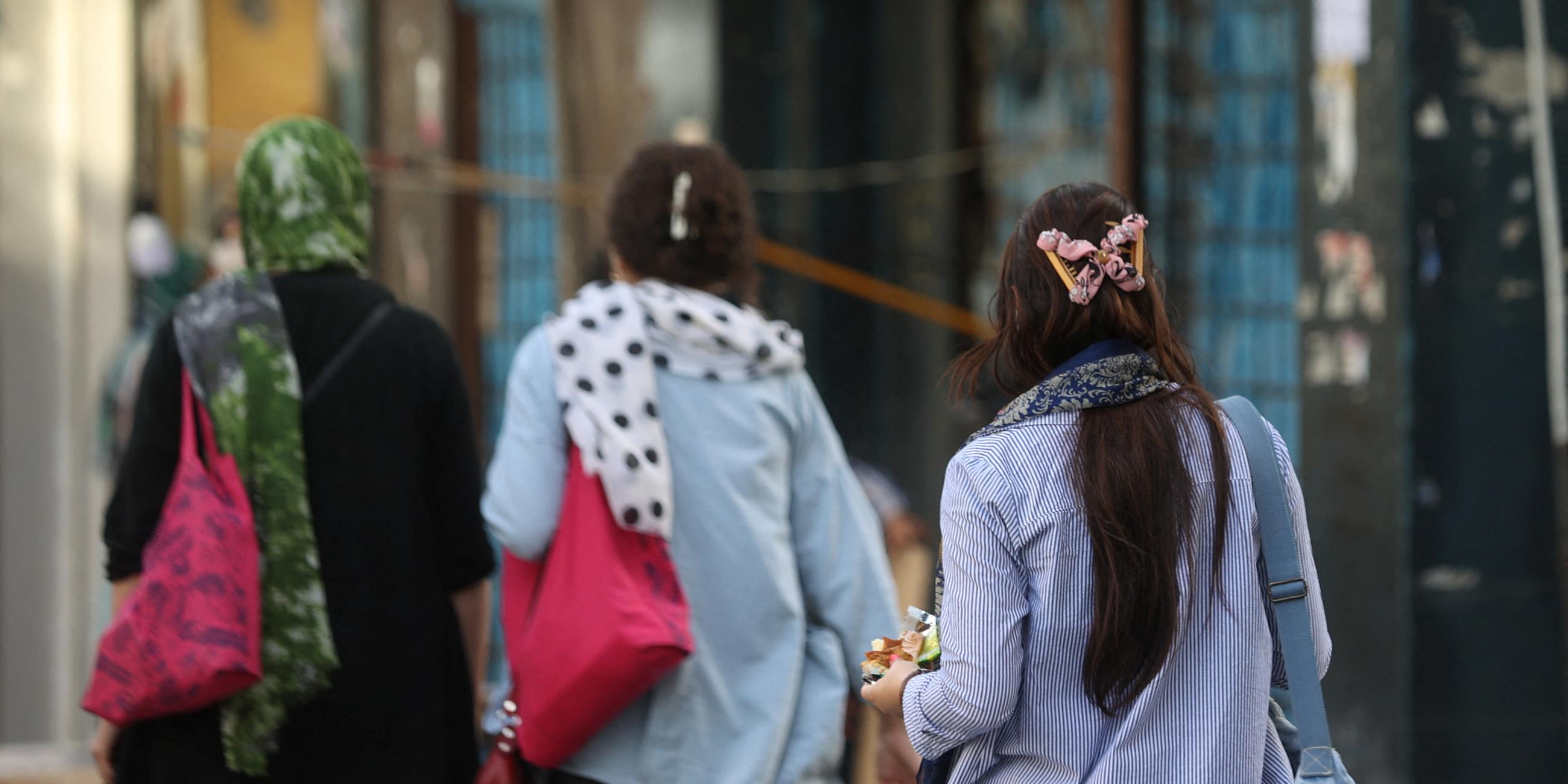 Iranische Frauen ohne und mit Kopftuch laufen auf öffentlicher Straße