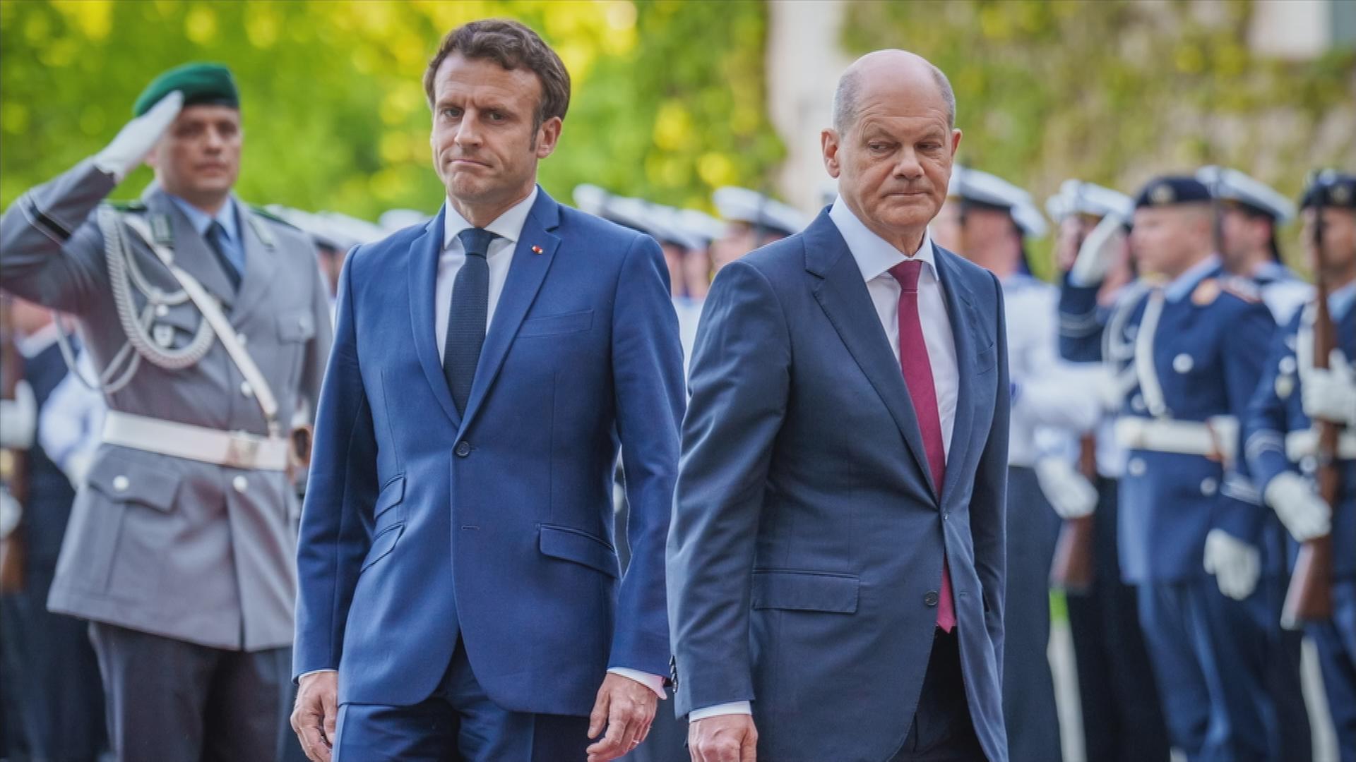 22.1.2023, Paris: Olaf Scholz und Emmanuel Macron stehen mit tristen Blicken nebeneinander.