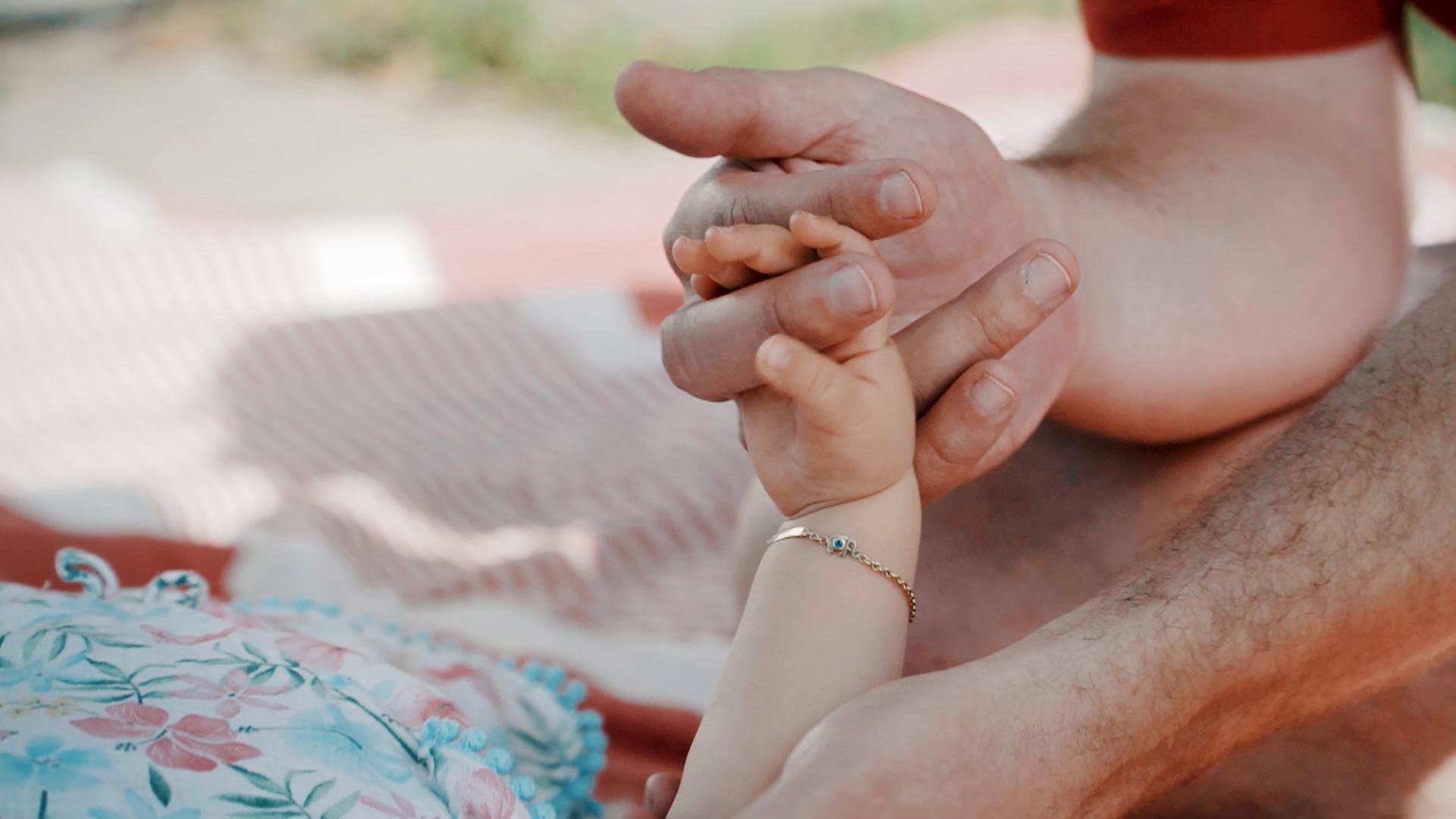Nahaufnahme: Hand eines Babys greift nach einer Männerhand.