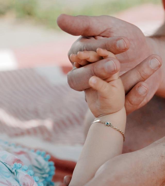 Nahaufnahme: Hand eines Babys greift nach einer Männerhand.