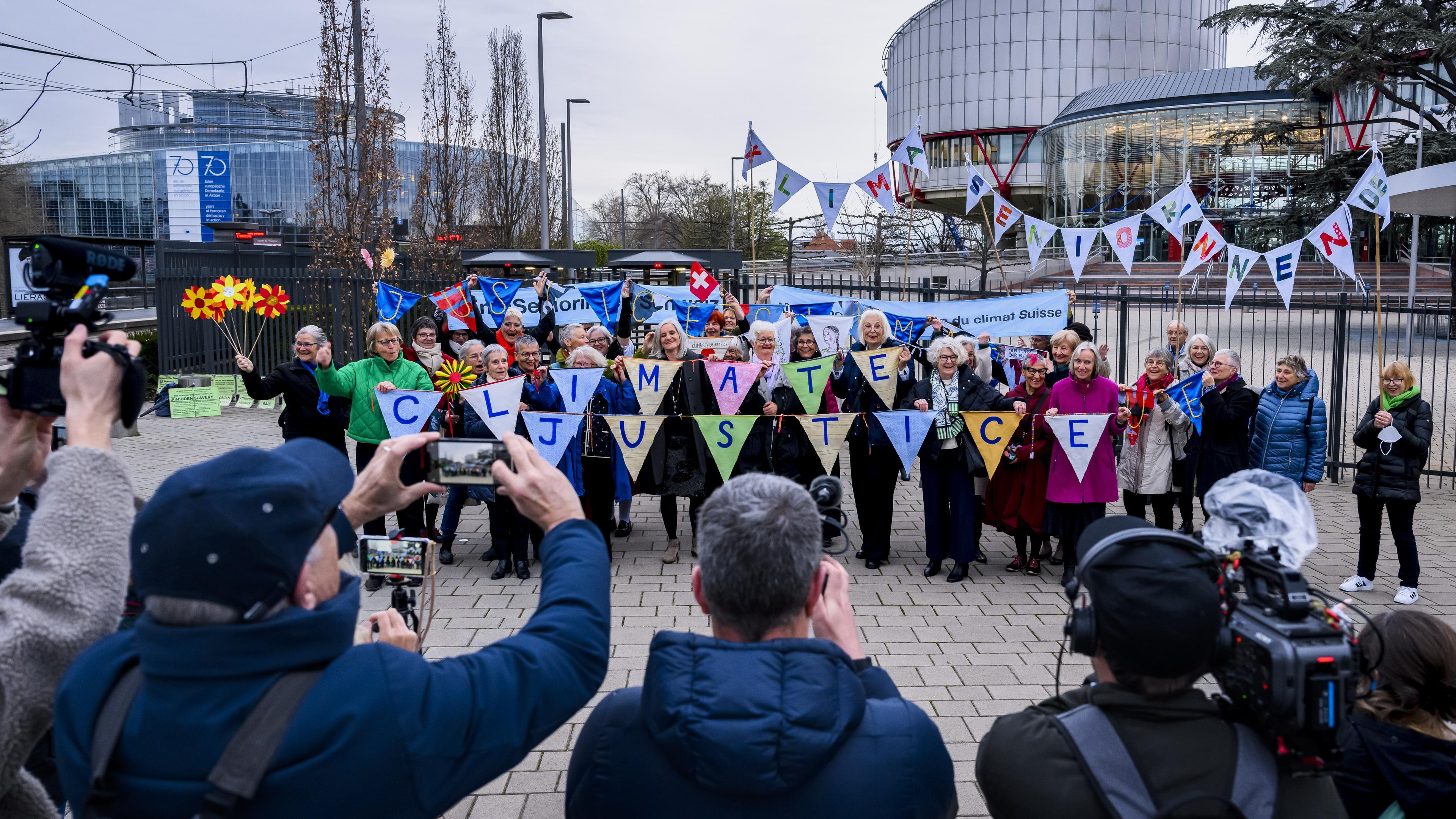 Eine Gruppe Frauen steht vor dem Europischen Gerichtshof. SIe halten ein Banner in Händen