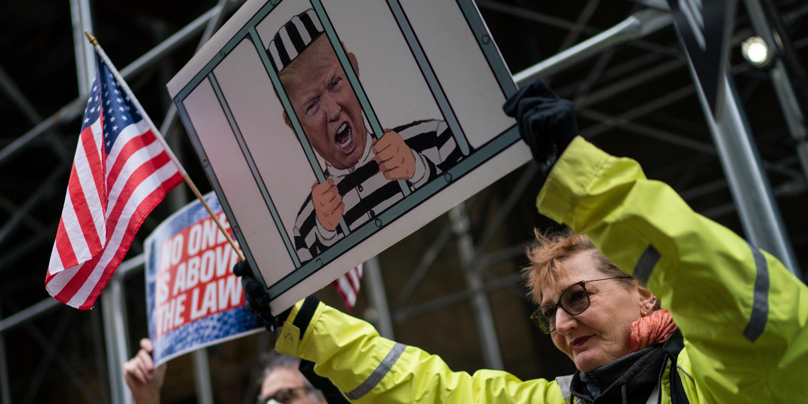 Frau hält Schild mit Trump hinter Gittern