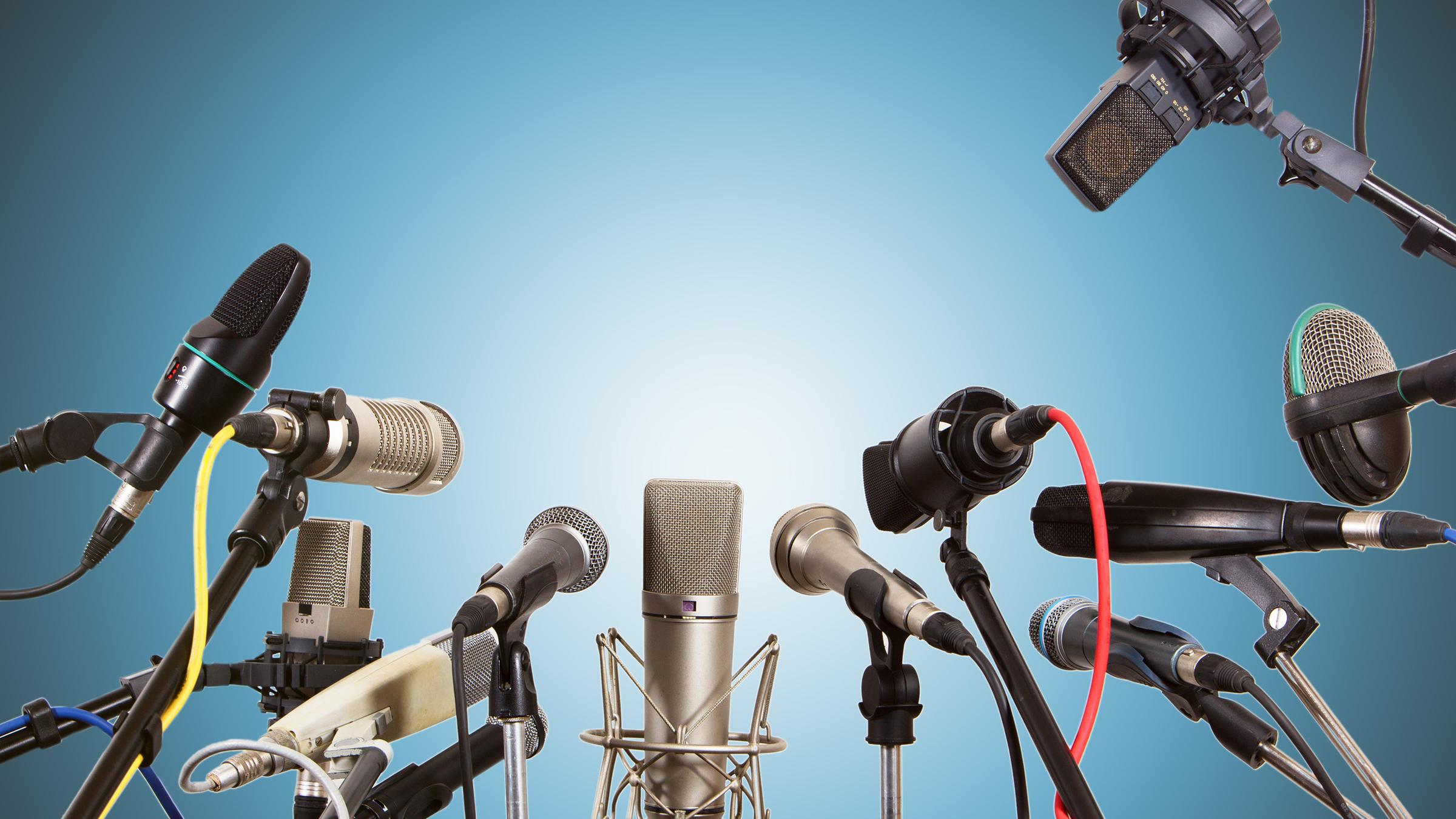 Mehrere MIkrofone in einer Runde vor blauem Hintergrund