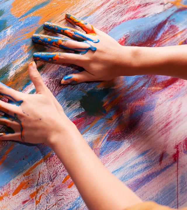 Hände mit Farbe malen auf einer bunten Leinwand