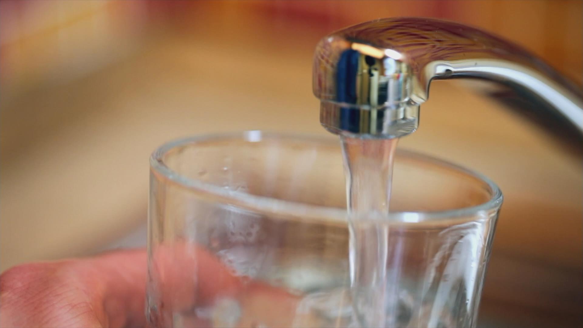 Wasser wird über ein Wasserhahn in ein Glas gefüllt
