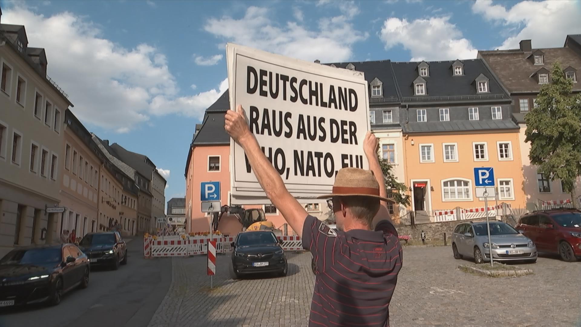 Mann hält Plakat nach oben "Deutschland raus aus der NATO/ EU"
