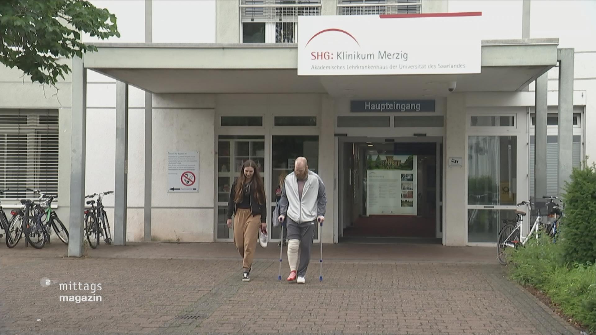 Haupteingang des Klinikum Merzig mit zwei Personen im Vordergrund