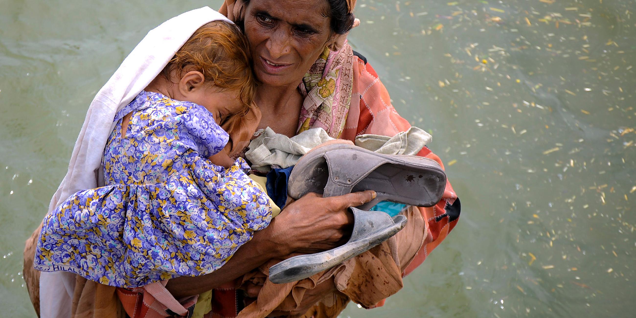 Frau mit Kind in Hochwasser in Pakistan