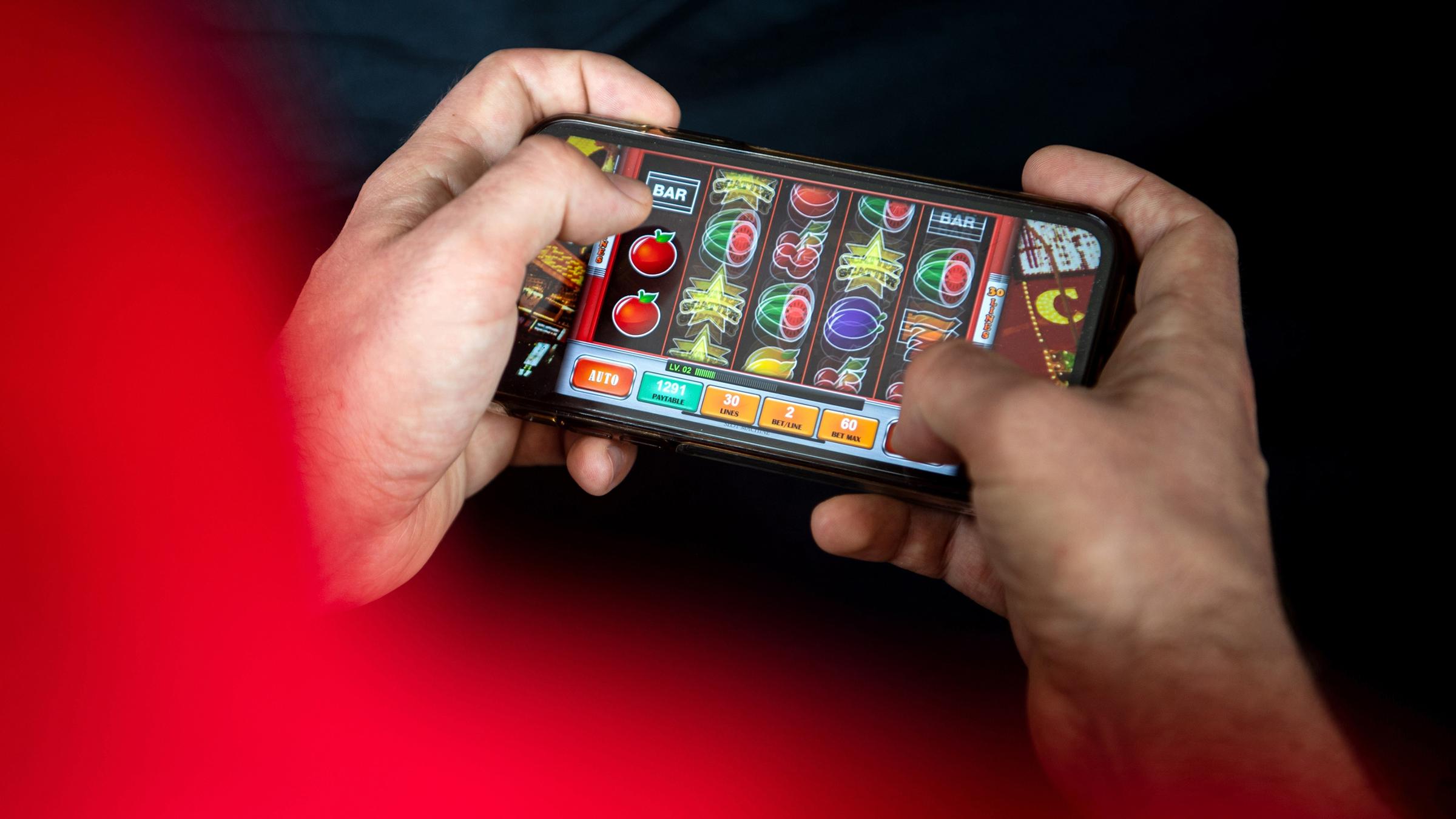 Zwei Hände halten ein Smartphone, darauf wird ein Online-Spiel gespielt.