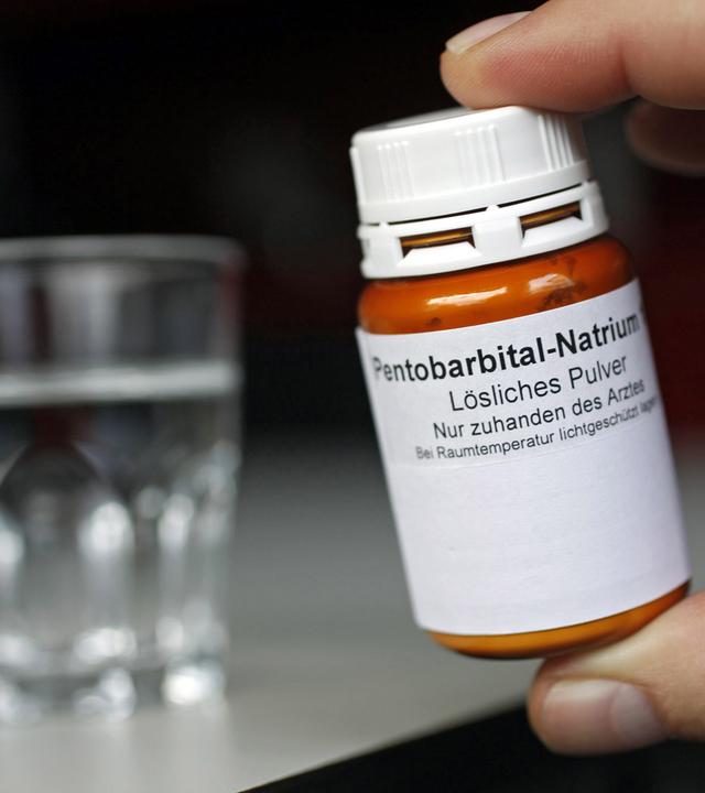 Toedliches Medikament neben einem Glas Wasser